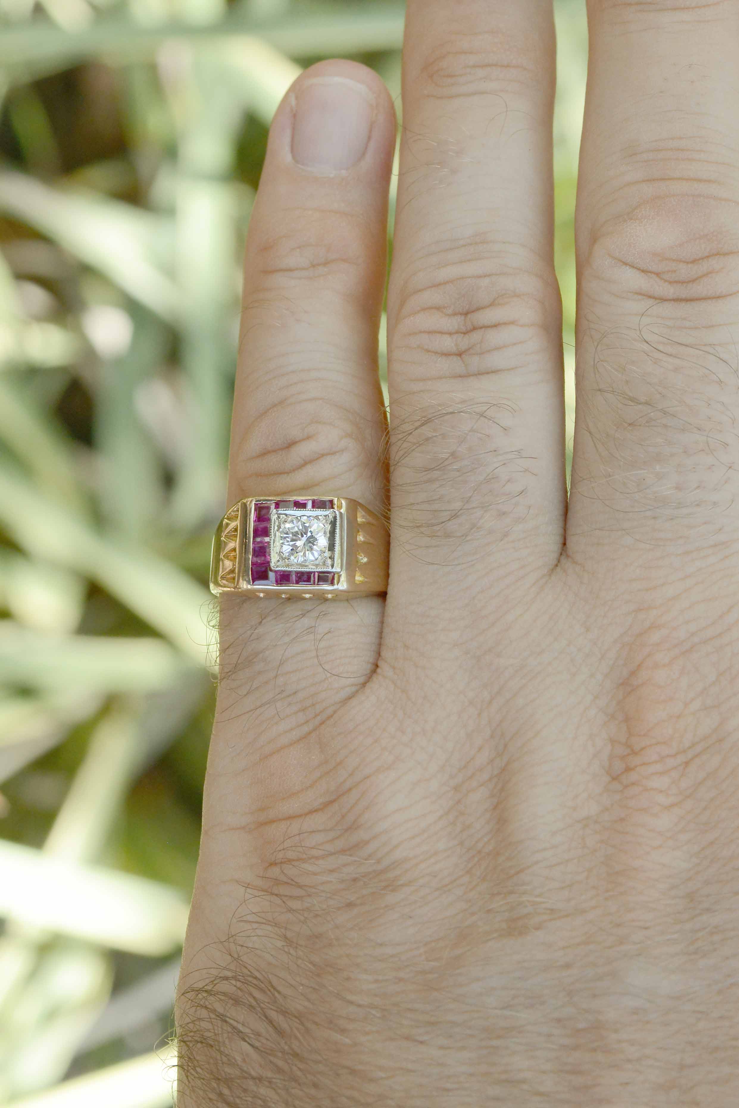 The center gemstone is a glimmering round brilliant cut diamond which is distinctively accented by 10 bezel set rubies.