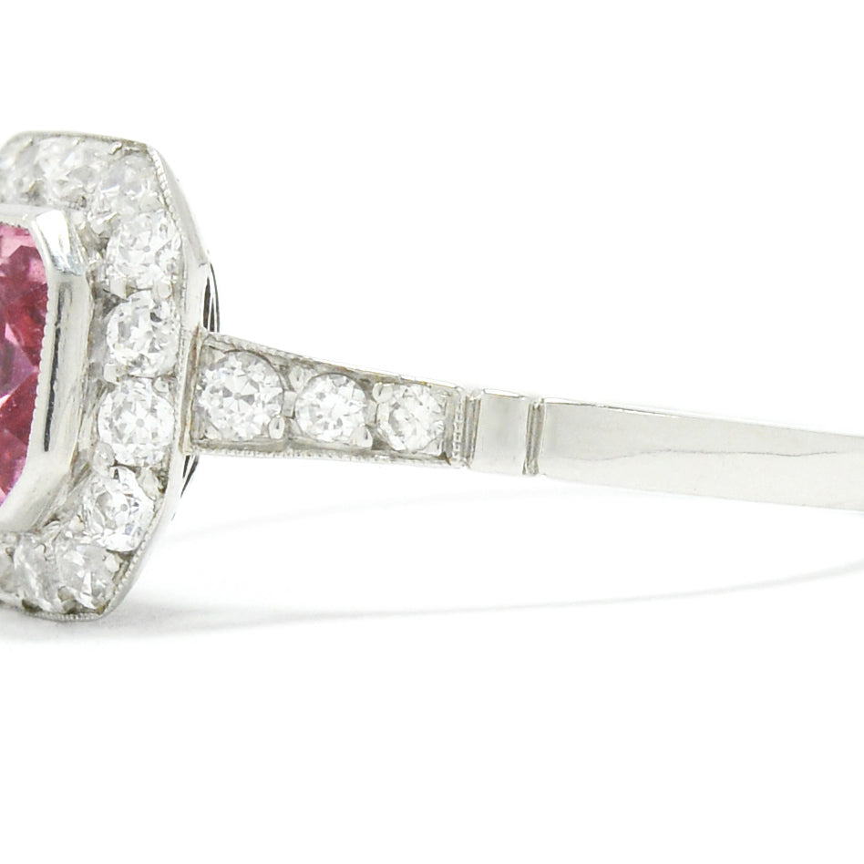 A low, bezel set sapphire is set in the center of an octagon shaped diamond halo ring.