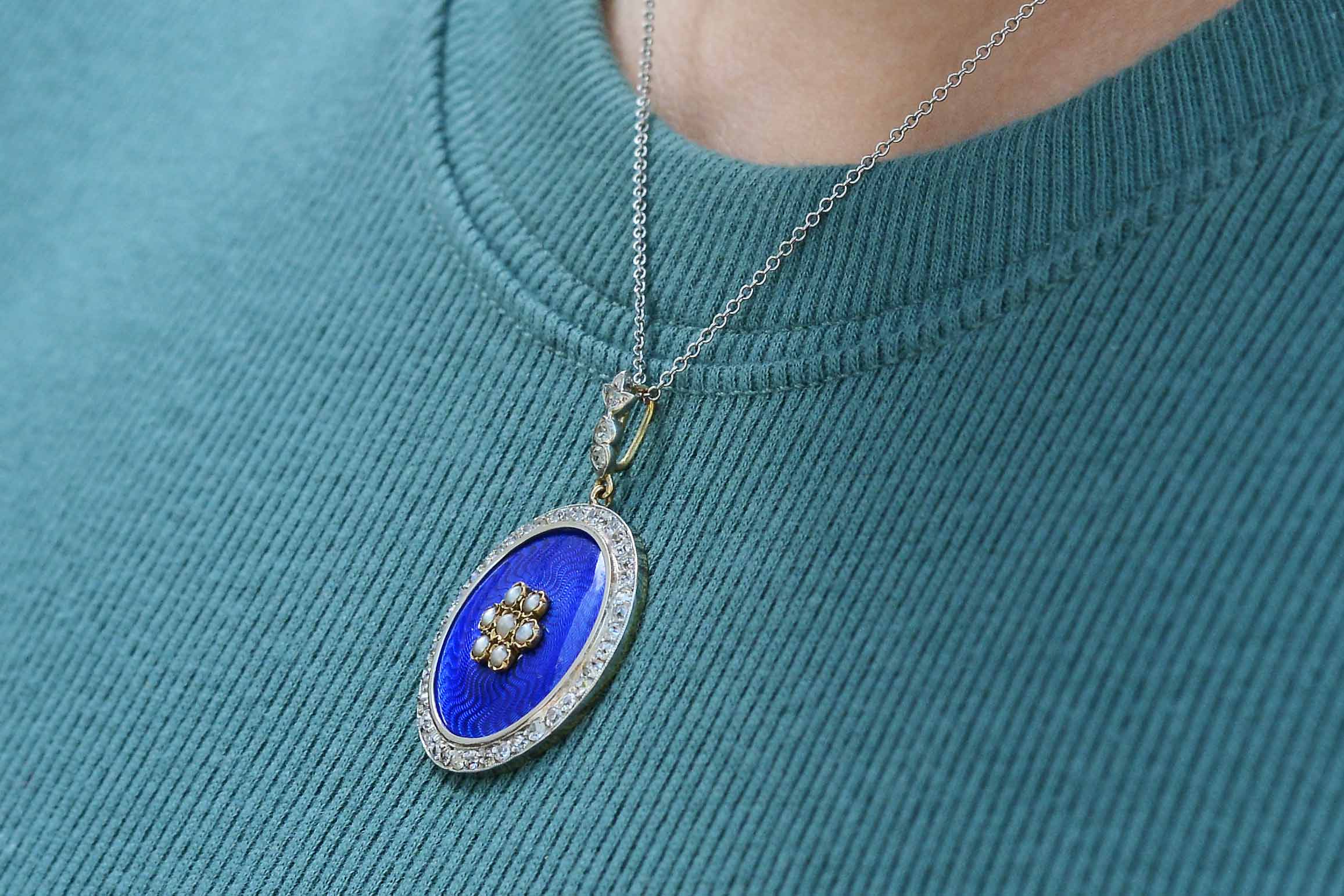 Rich, shimmering royal blue enamel lines this diamond halo pendant necklace.