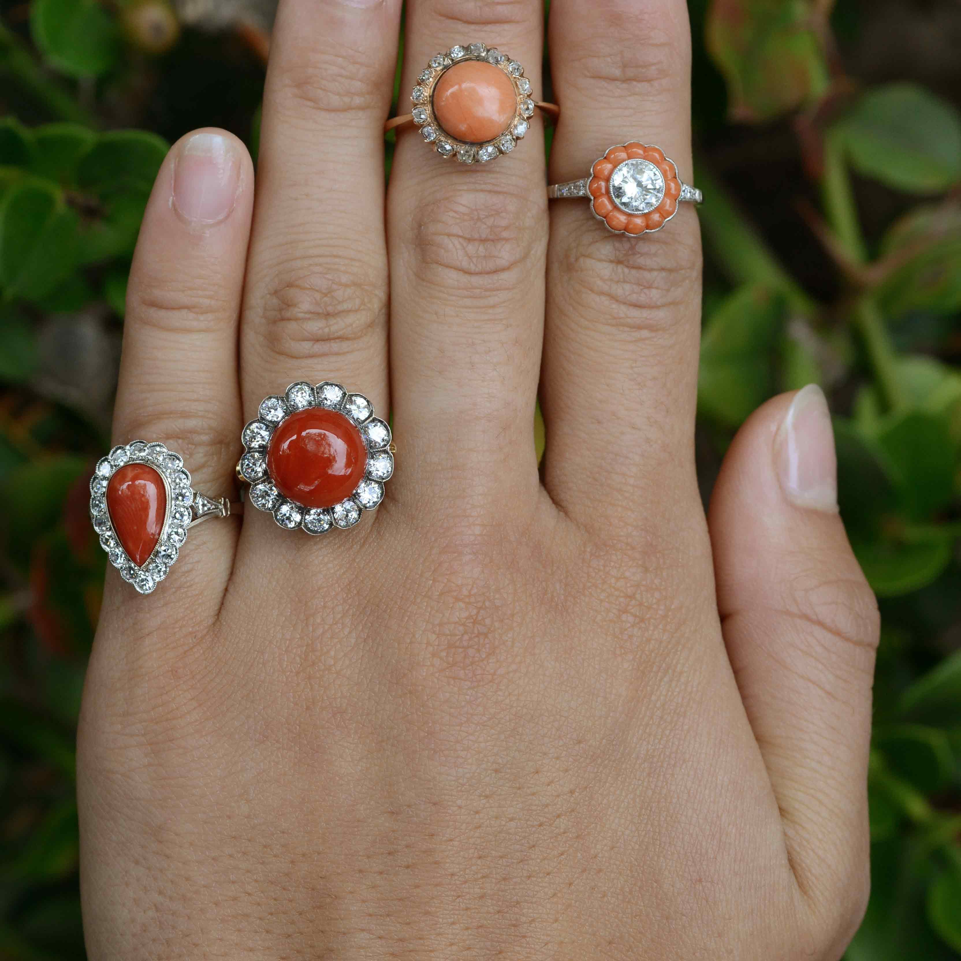 Round coral diamond halo statement rings.