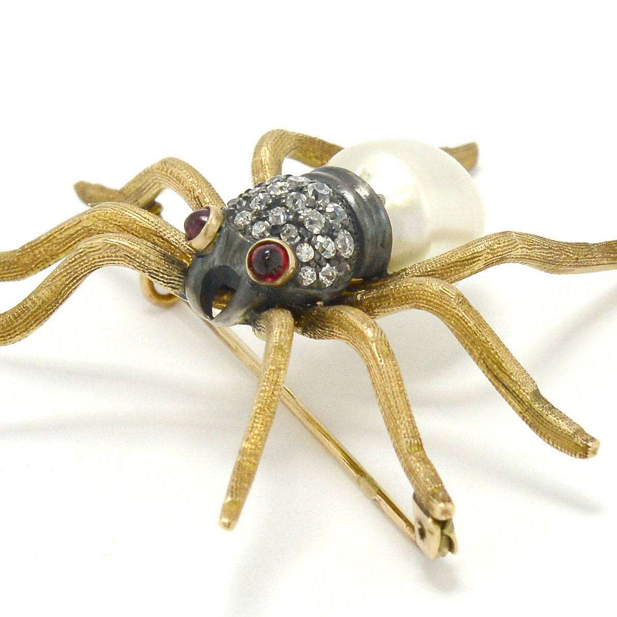 An antique Victorian spider pin made of gold, rubies, diamonds and pearl.