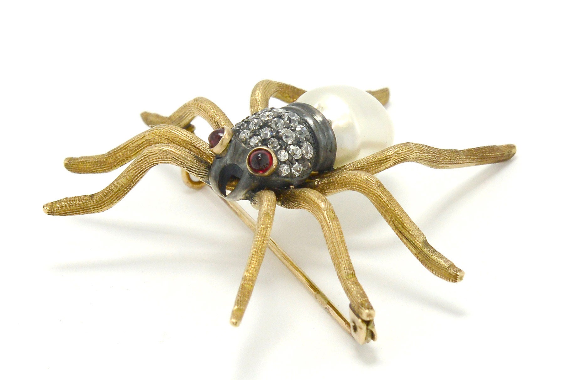 An antique Victorian spider pin made of gold, rubies, diamonds and pearl.