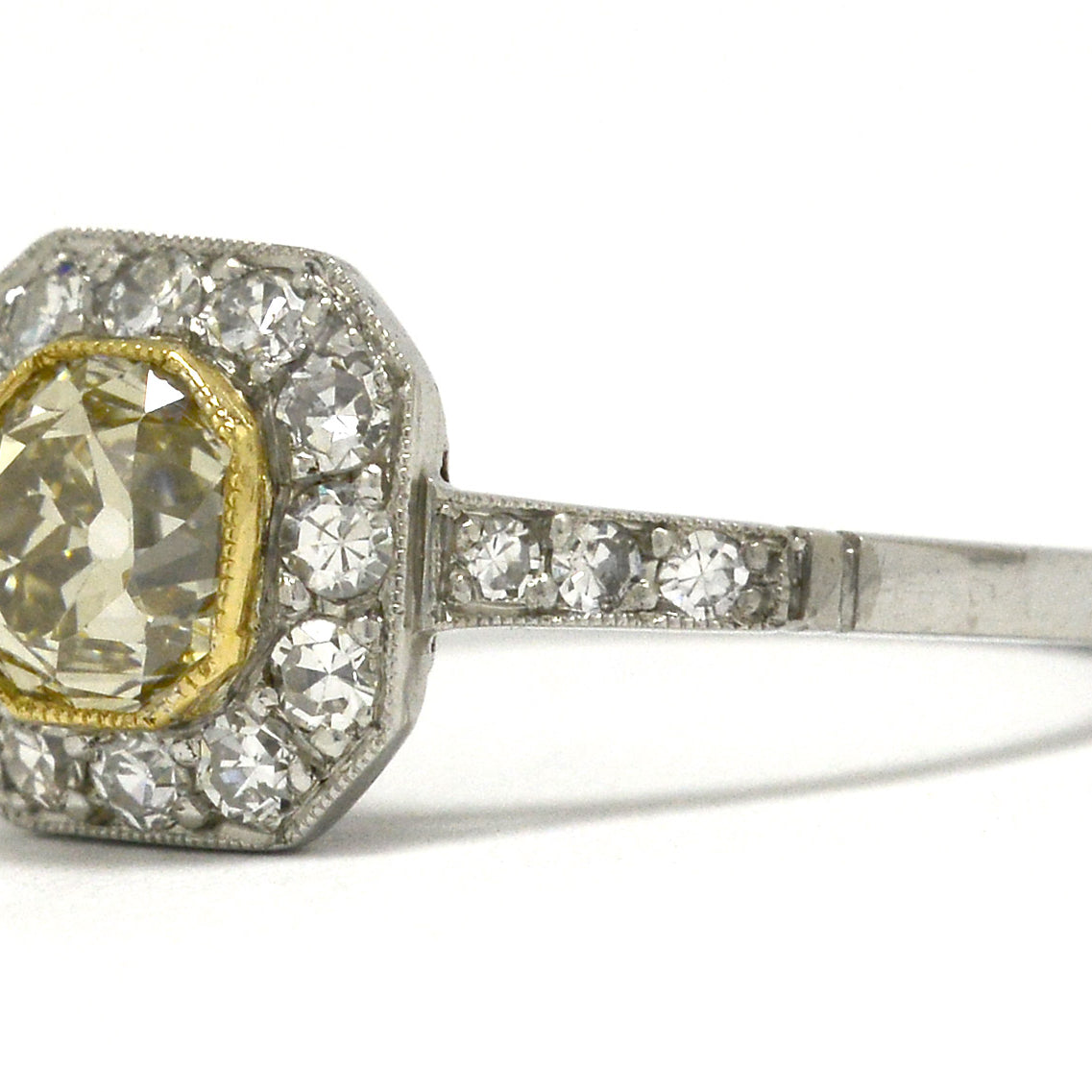 An old mine cushion diamond of light yellow color, set in a platinum ring.