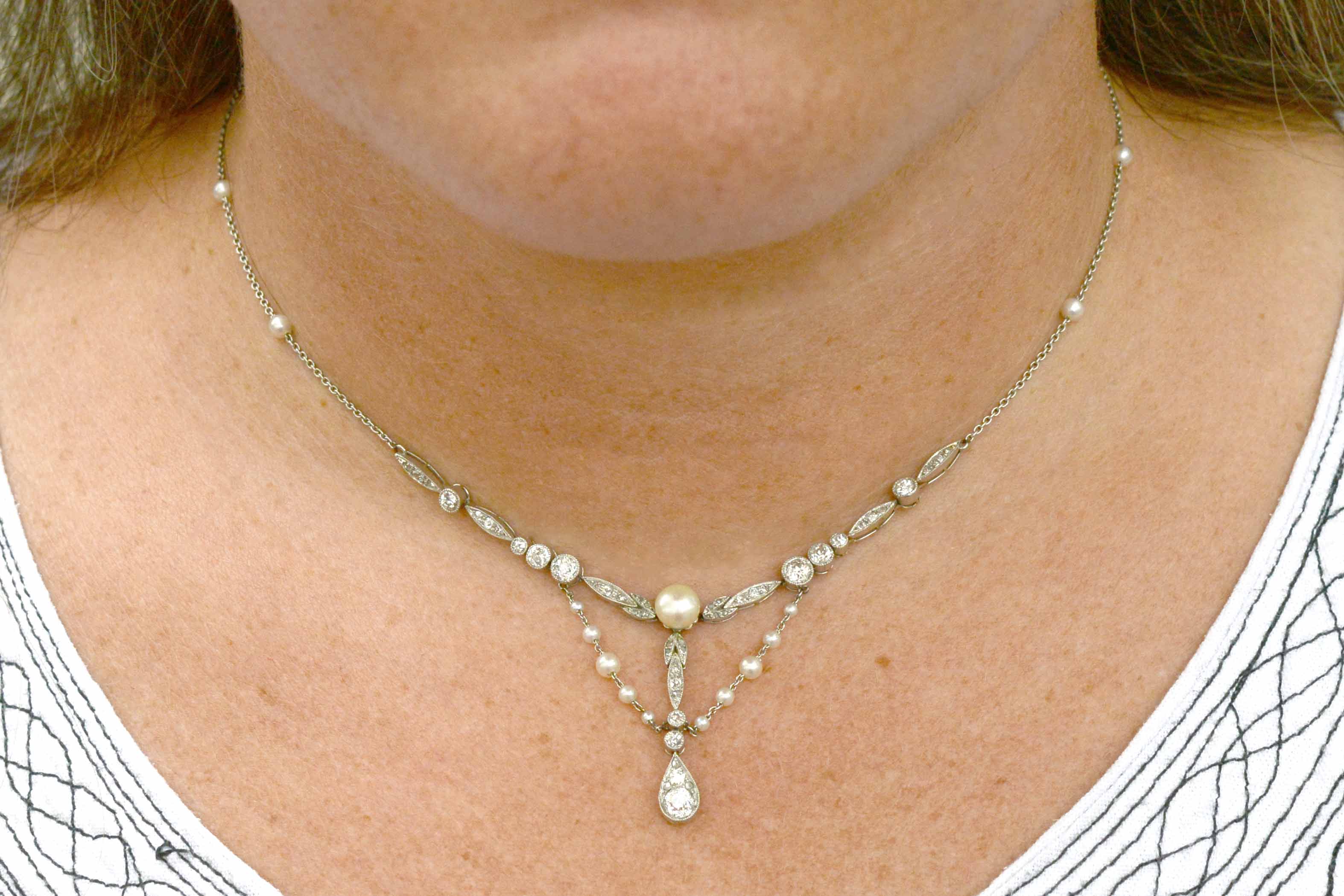 An Edwardian bib style platinum lavalier necklace with pearl drapes.
