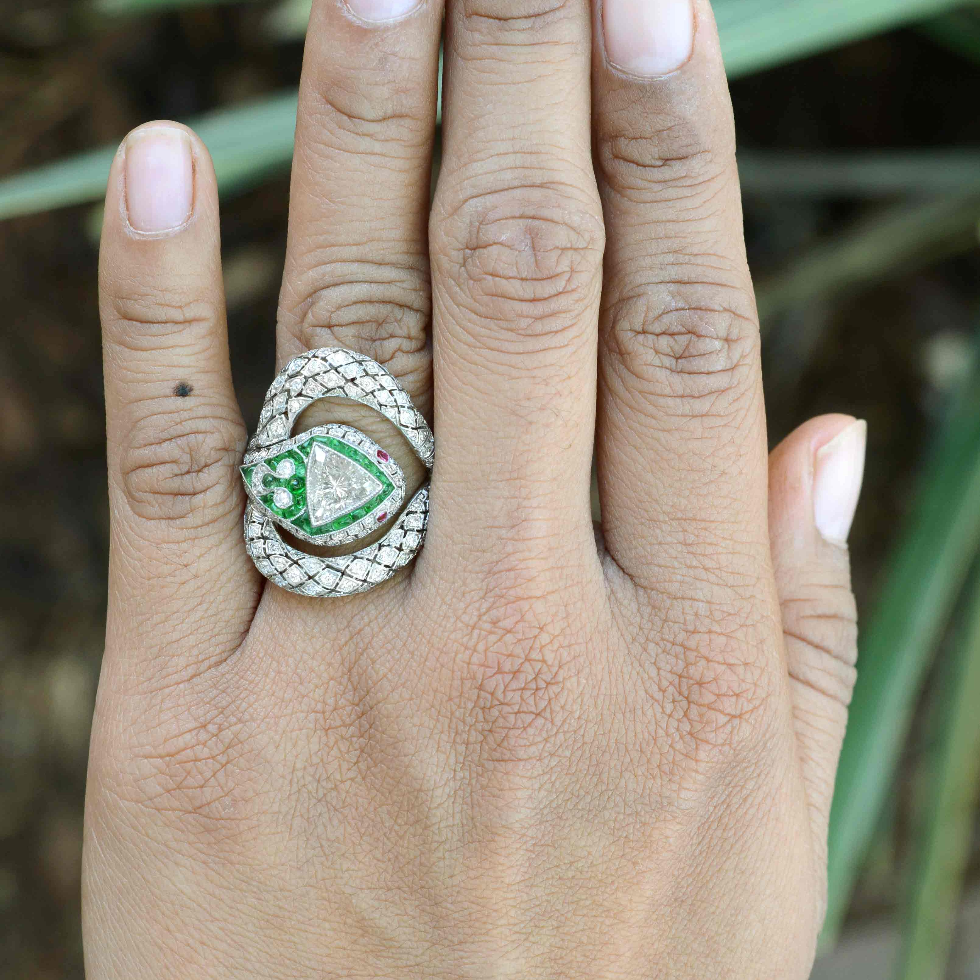 An Art Deco platinum snake diamond, emerald and rubies ring.
