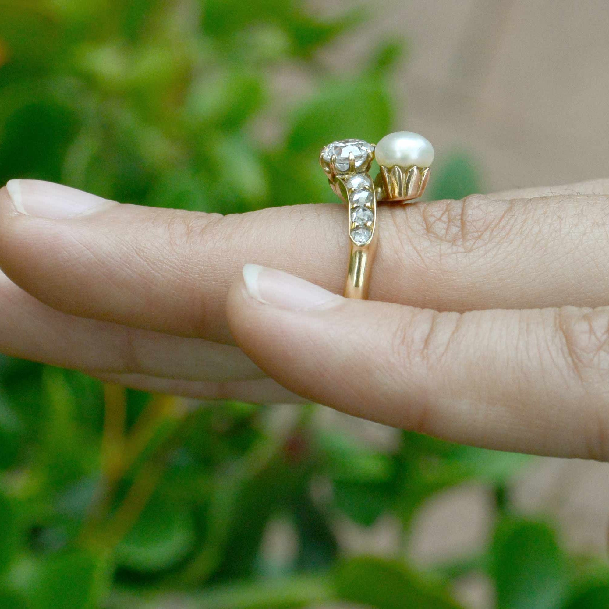 This gold wedding ring features a diamond and pearl in the center.