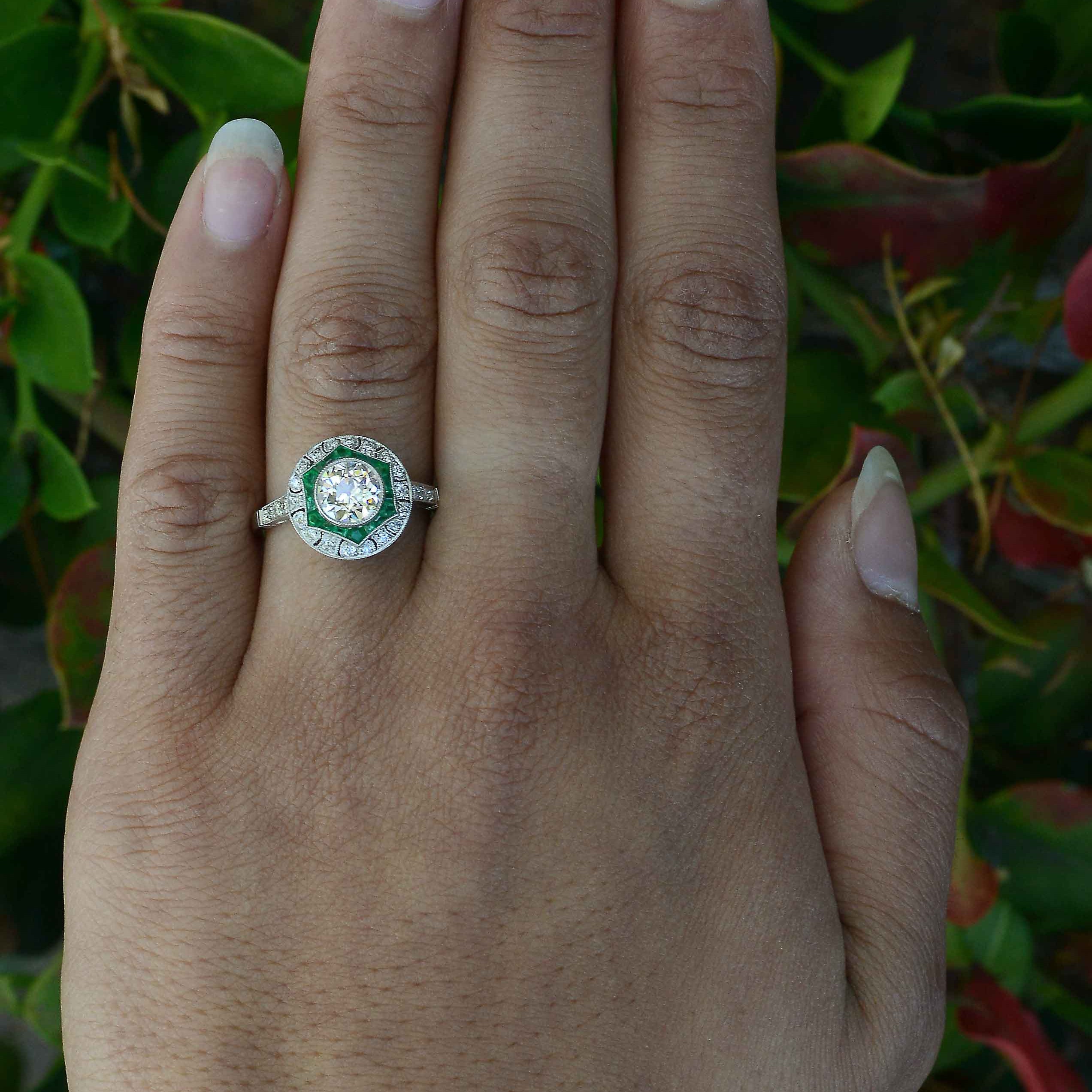 A diamond and emerald star design platinum engagement ring.