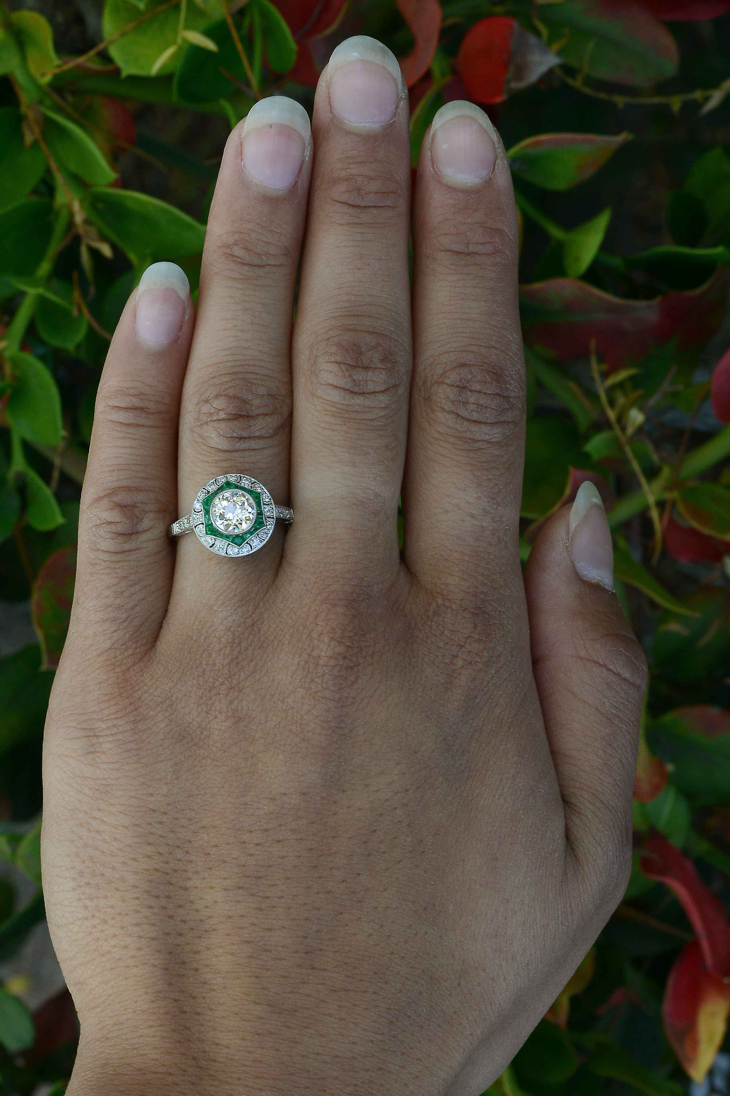 A diamond and emerald star design platinum engagement ring.