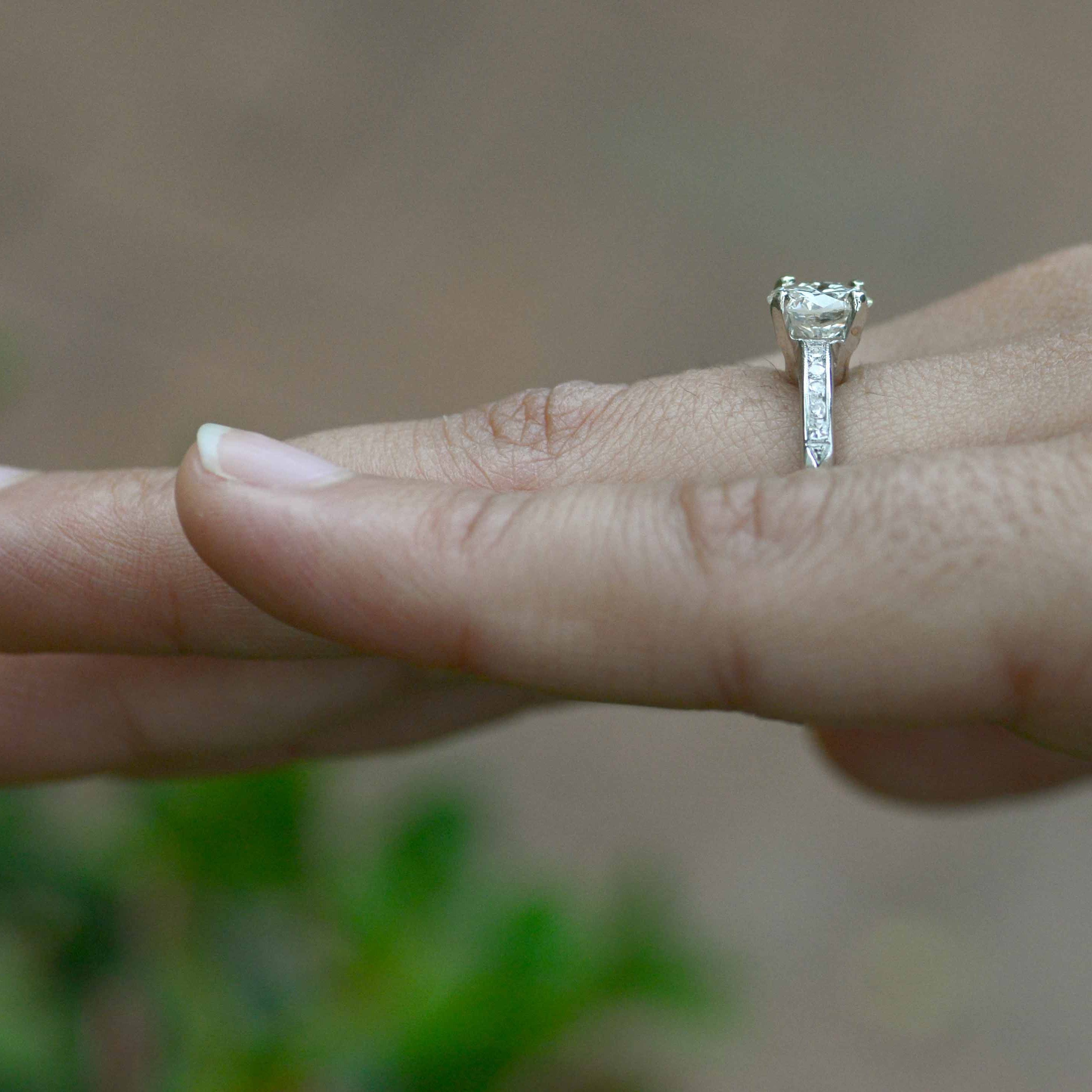 A vintage diamond solitaire ring with gemstones on the band.