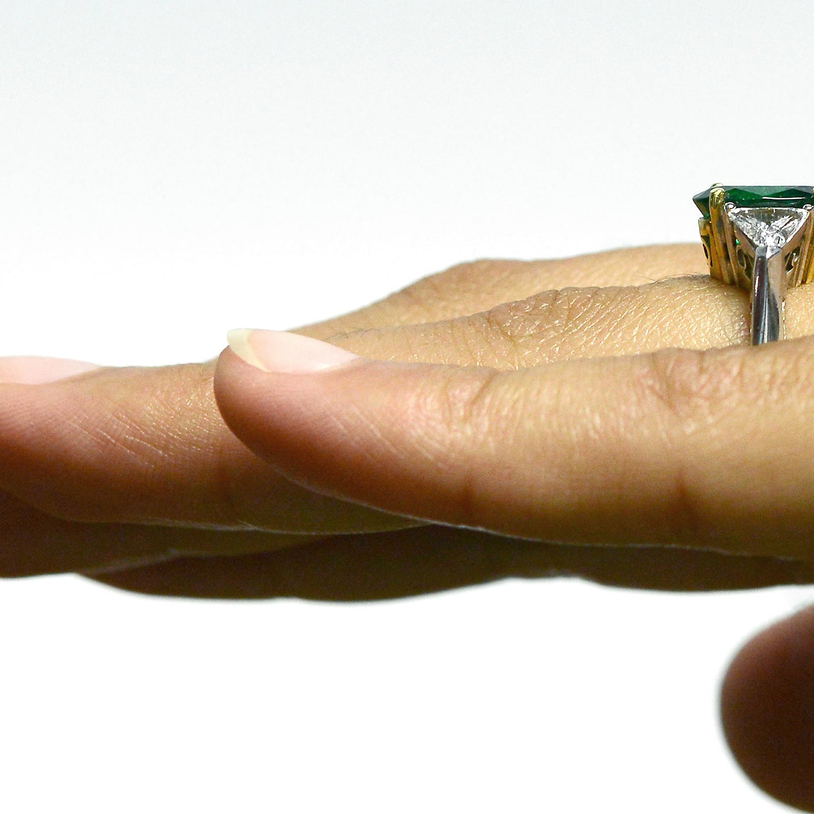2 triangle diamonds accent the large oval emerald in this engagement ring.