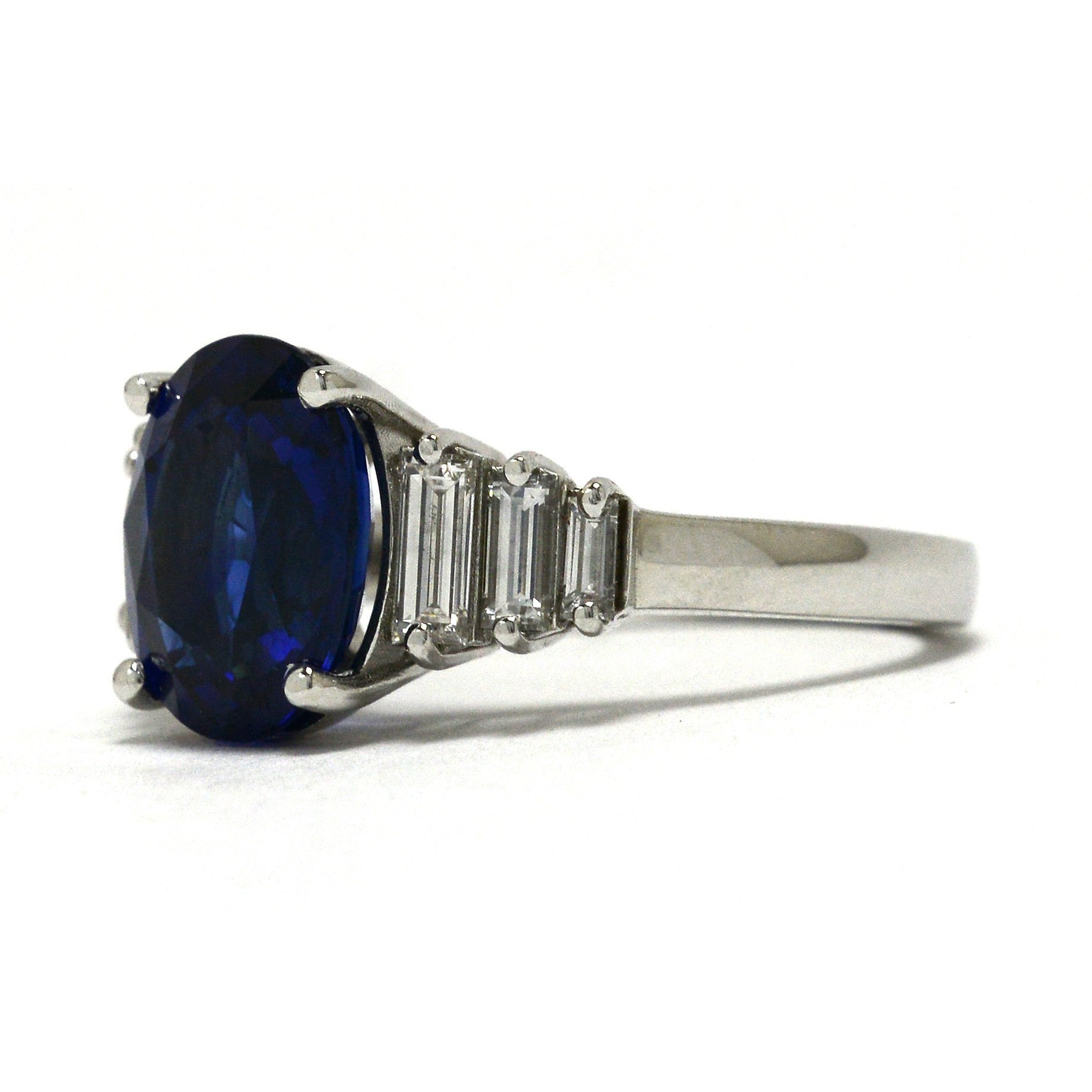 A four carat oval blue sapphire set in a diamond steps, tapered band engagement ring.