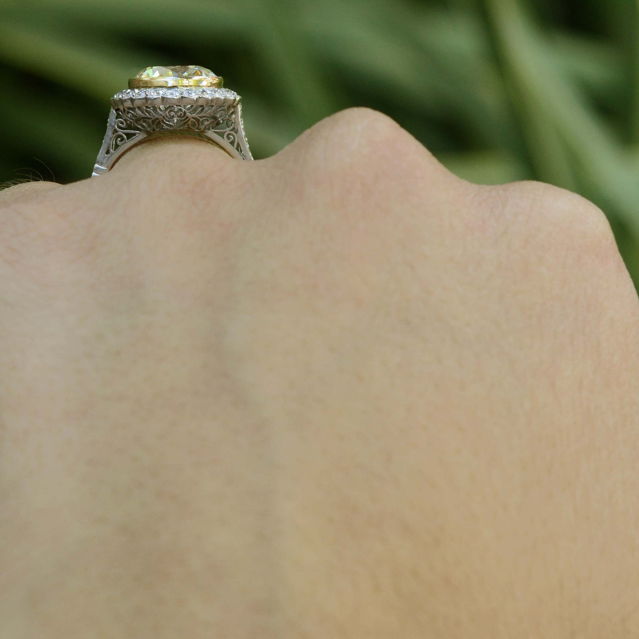 A scalloped halo of diamonds surround the round brilliant yellow diamond in this Art Deco style engagement ring.