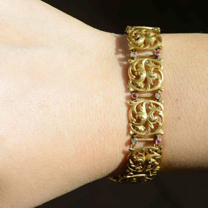 A flower design 18k yellow gold link bracelet with diamonds and rubies.