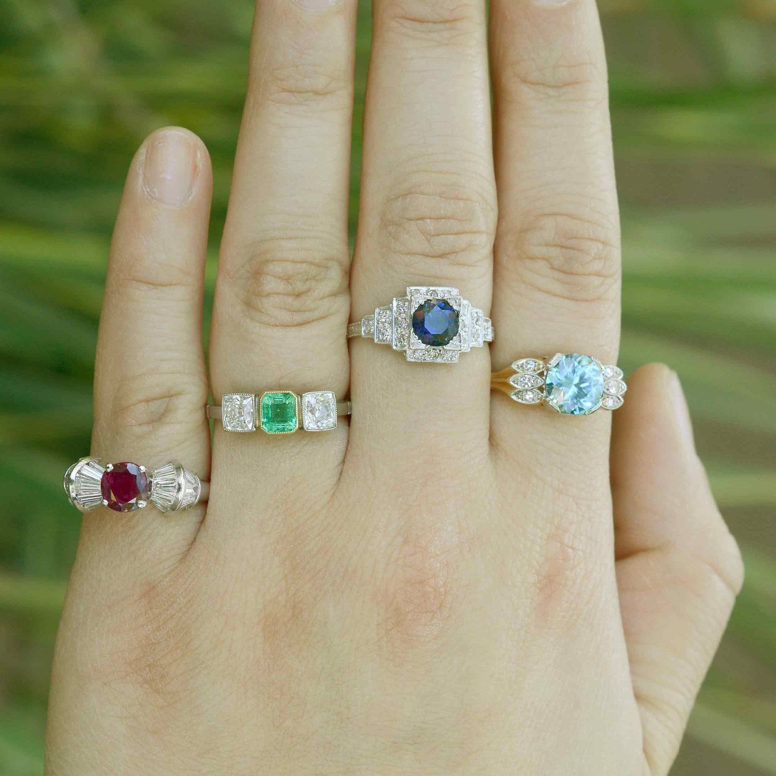 Ruby, emerald and sapphire engagement rings with diamond accents.