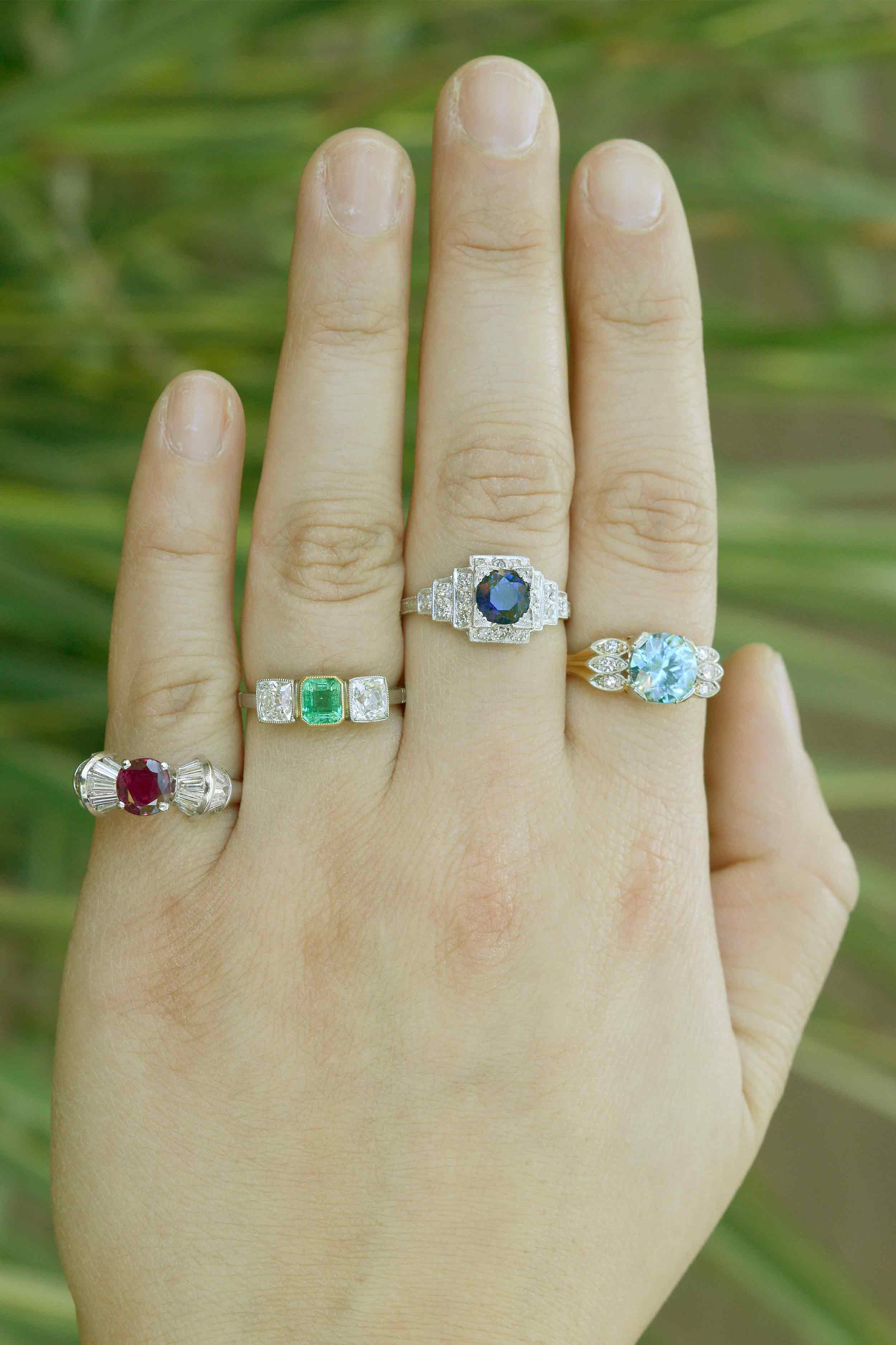 Ruby, emerald and sapphire engagement rings with diamond accents.
