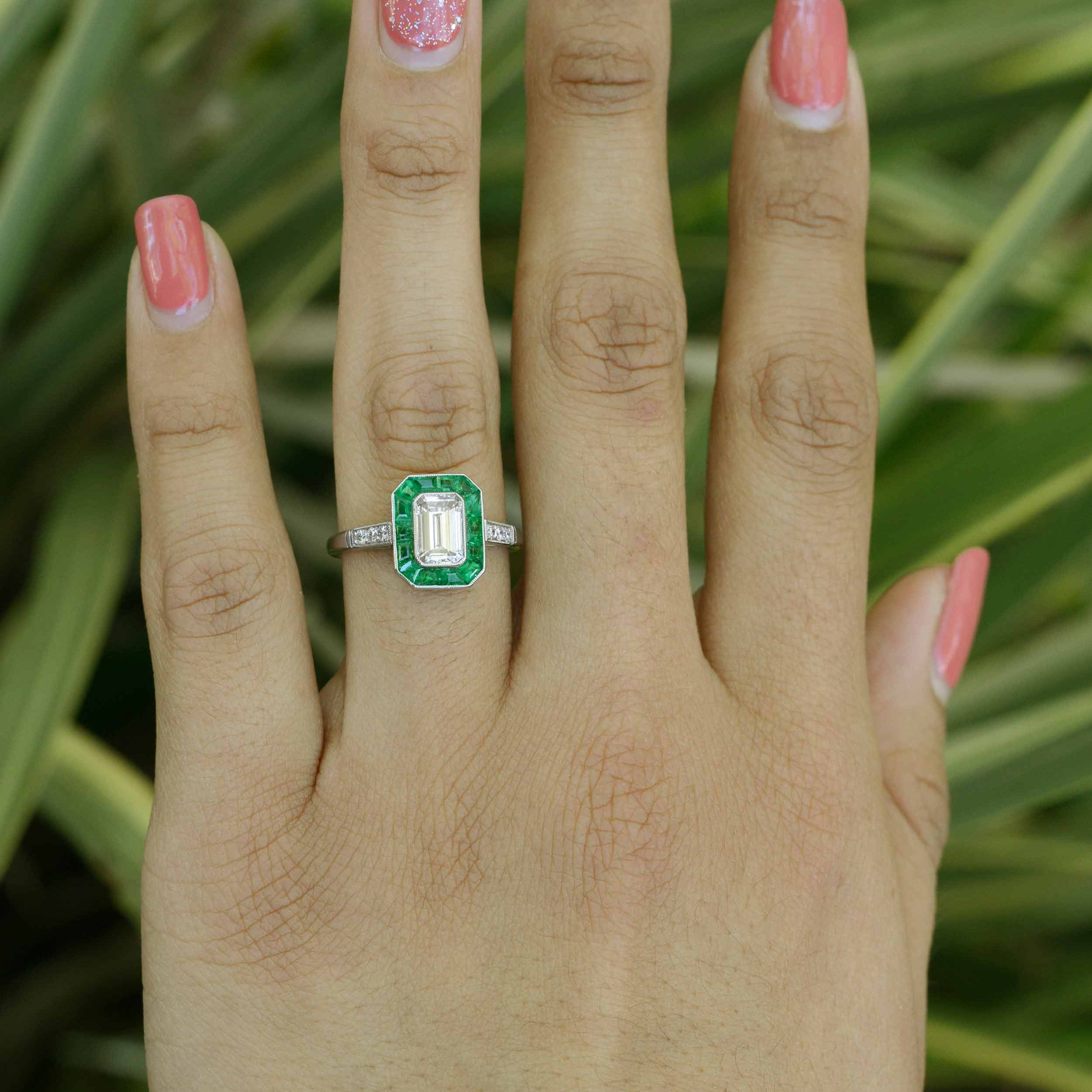 French cut emeralds surround the one carat emerald cut diamond.