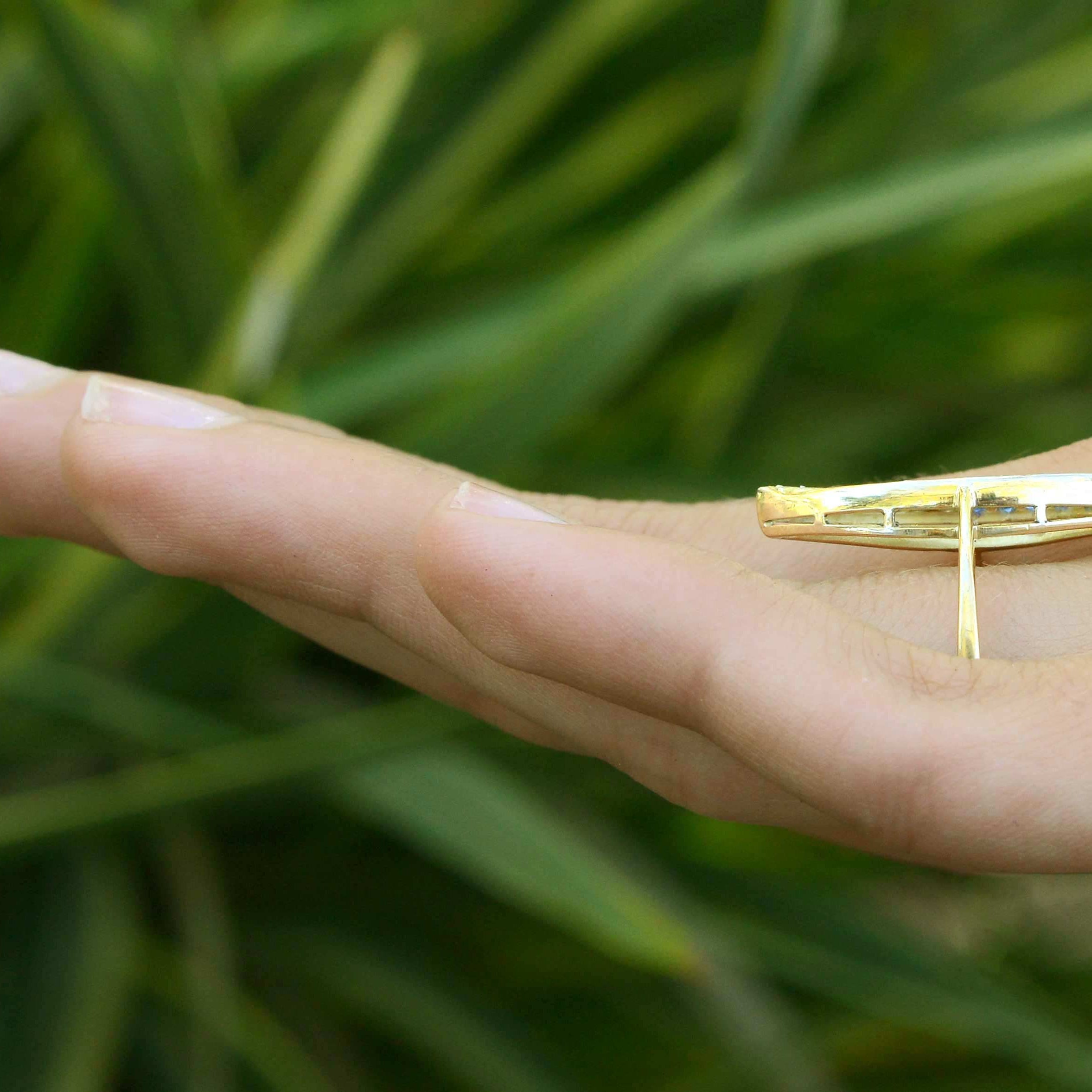 A narrow gold navette ring, topped with blue sapphires and diamonds.