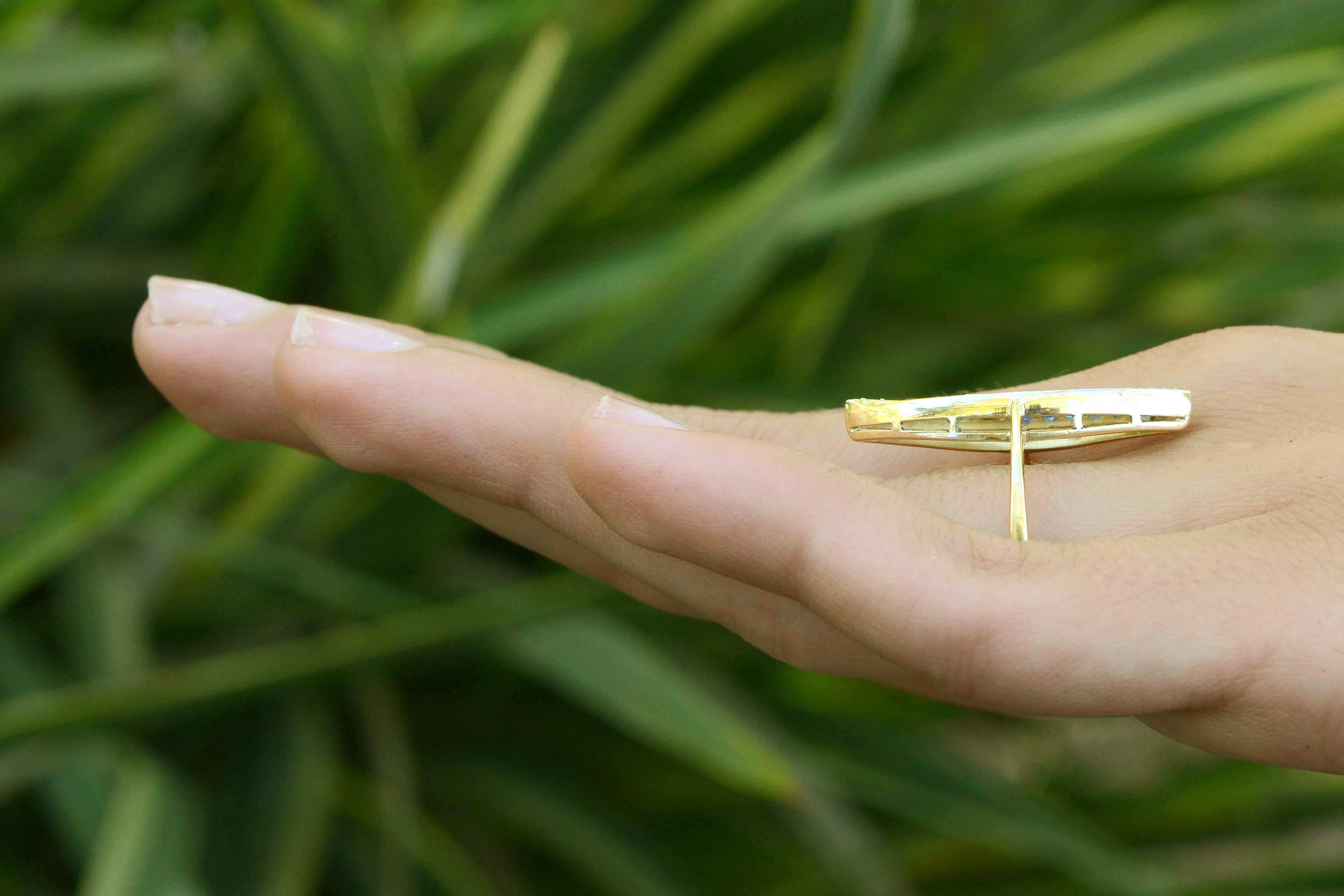 A narrow gold navette ring, topped with blue sapphires and diamonds.