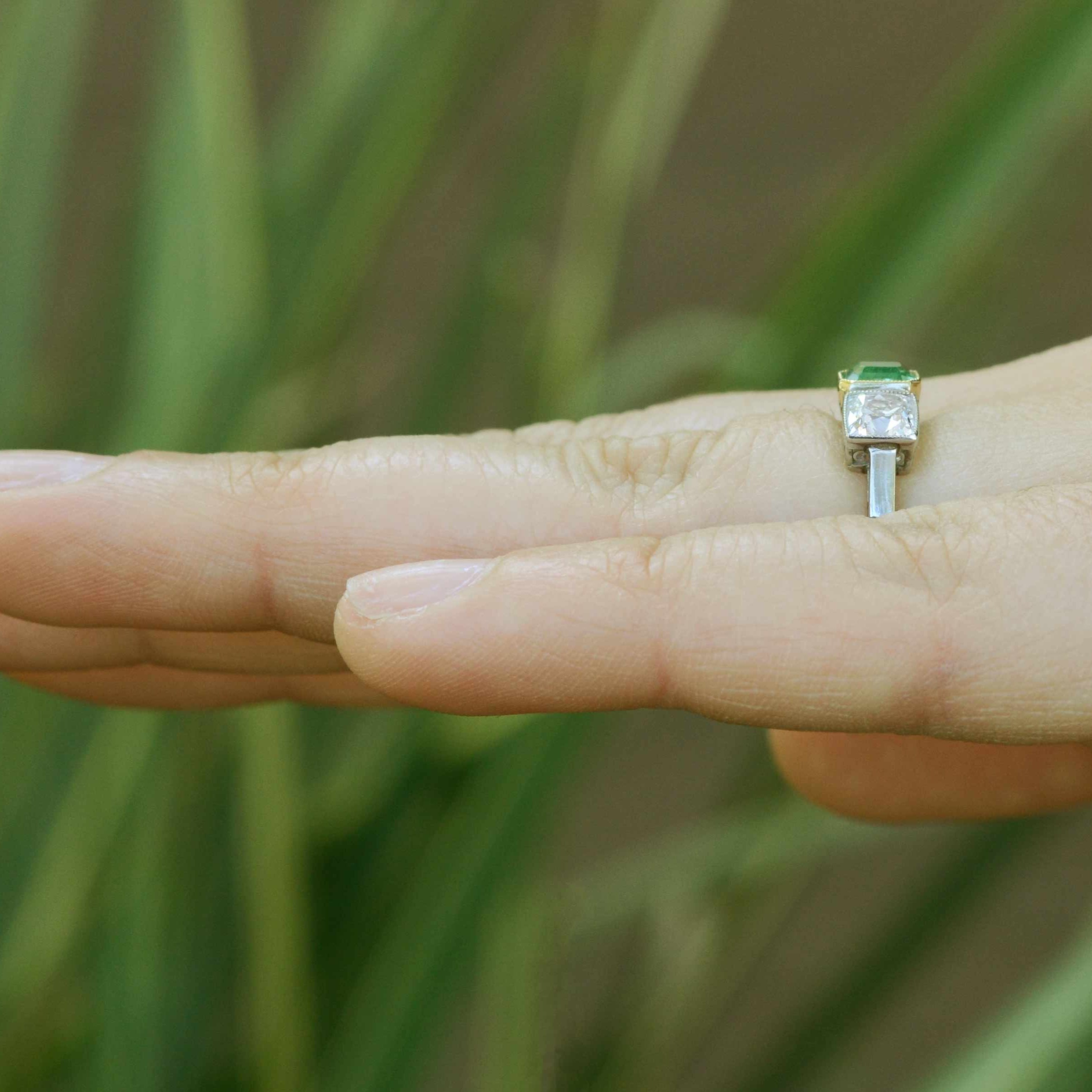 An emerald cut emerald with 2 square cushion diamonds ring.