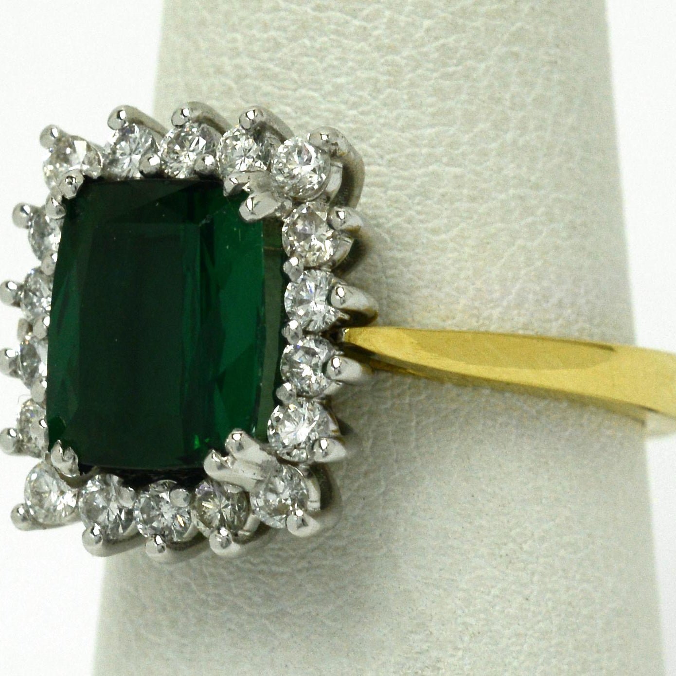 A modern classic three carat cushion green tourmaline ring, set with a halo of diamonds.