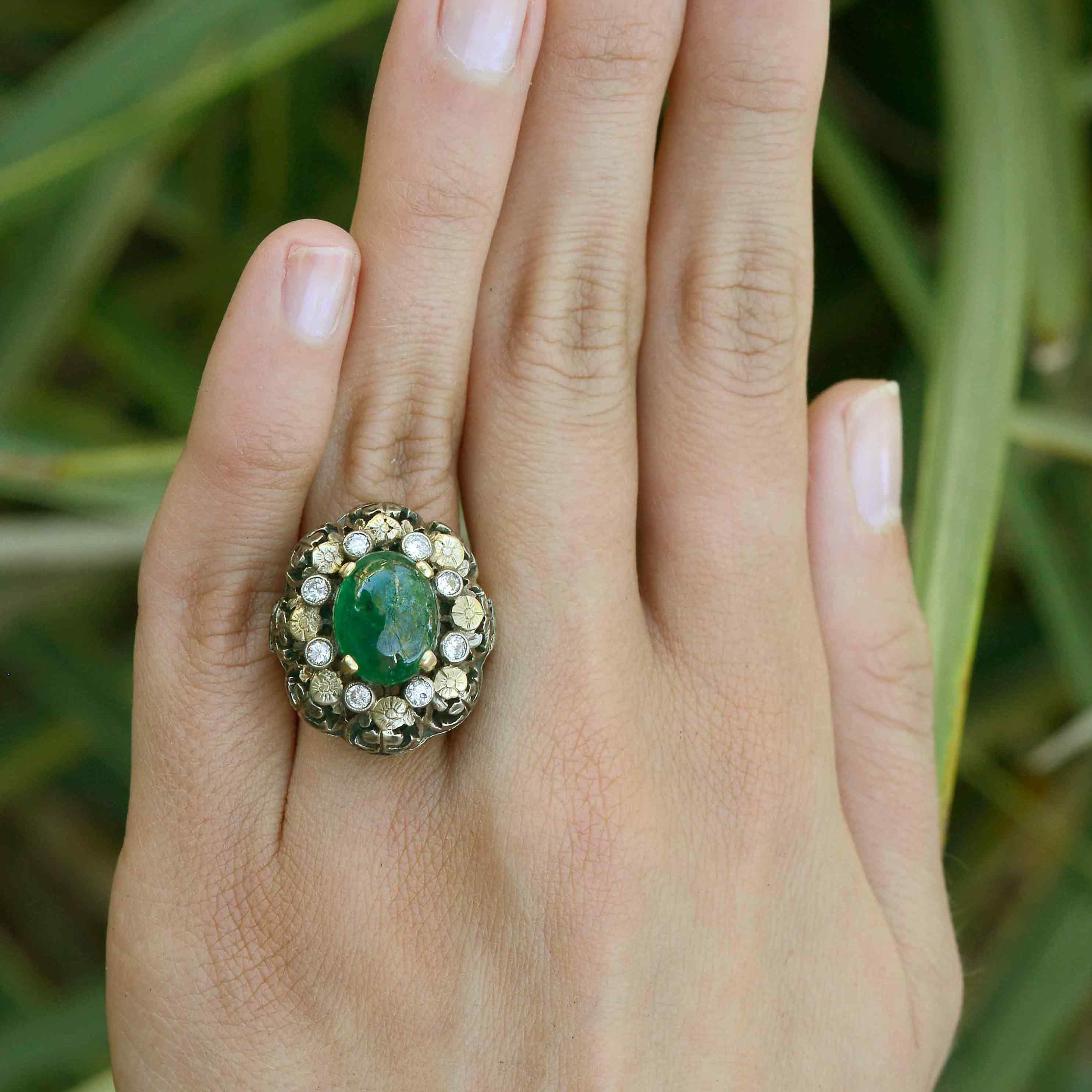 A diamond and flower halo ring with a three carat oval cabochon emerald.