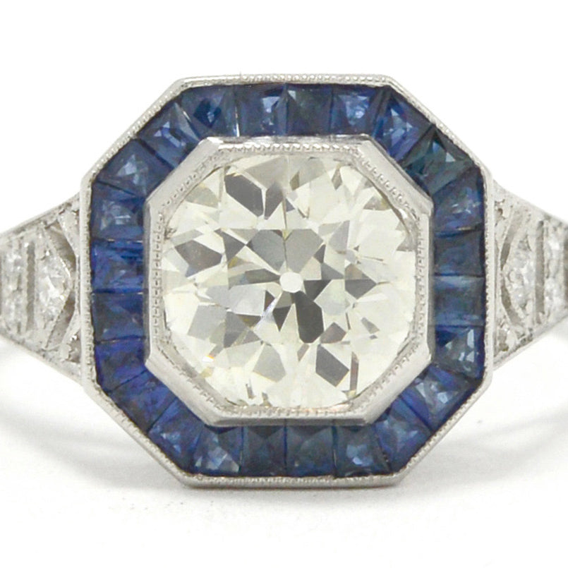 A natural old mine brilliant diamond engagment ring with a halo of blue sapphires.