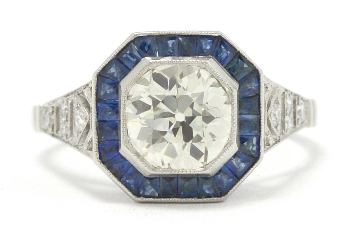A natural old mine brilliant diamond engagment ring with a halo of blue sapphires.