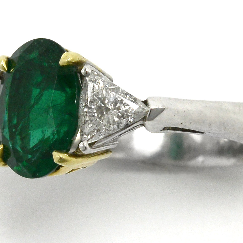 An oval emerald and 2 triangle diamond trinity ring.