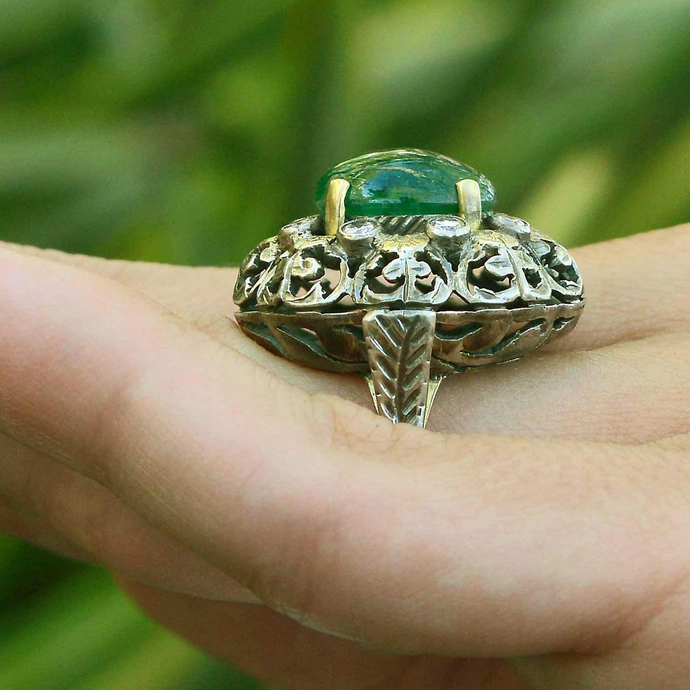 A silver and yellow gold Victorian floral dome ring with a large oval emerald.