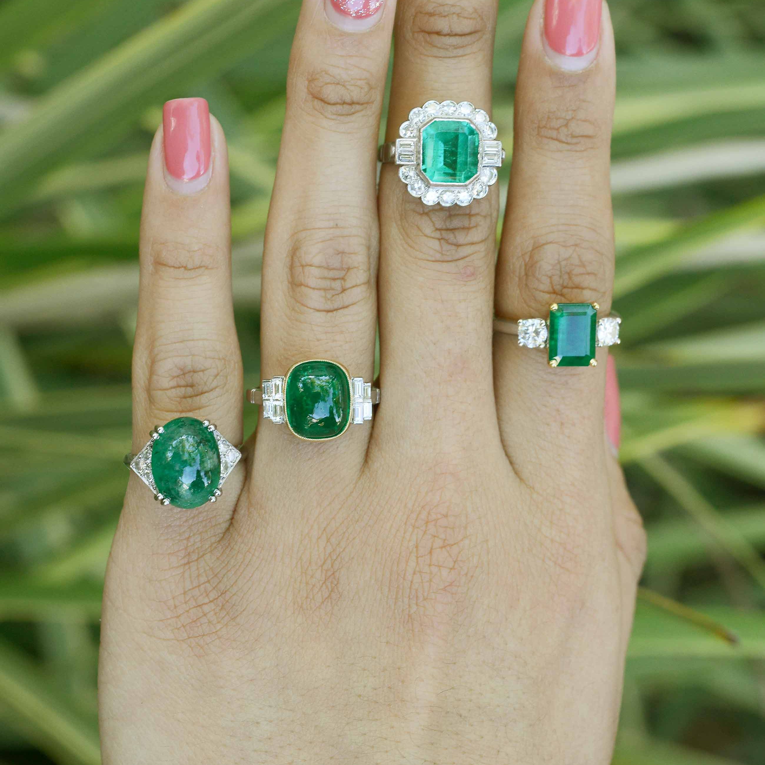 Large emerald platinum engagement rings accented by diamonds.