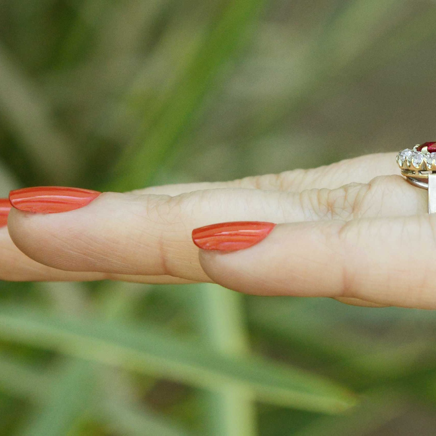11 old mine cut diamonds encircle the bright red antique cushion cut ruby.