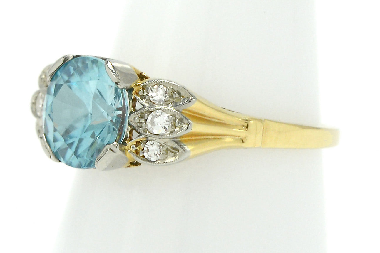 A radiating 18k gold band supporting a neon blue zircon.