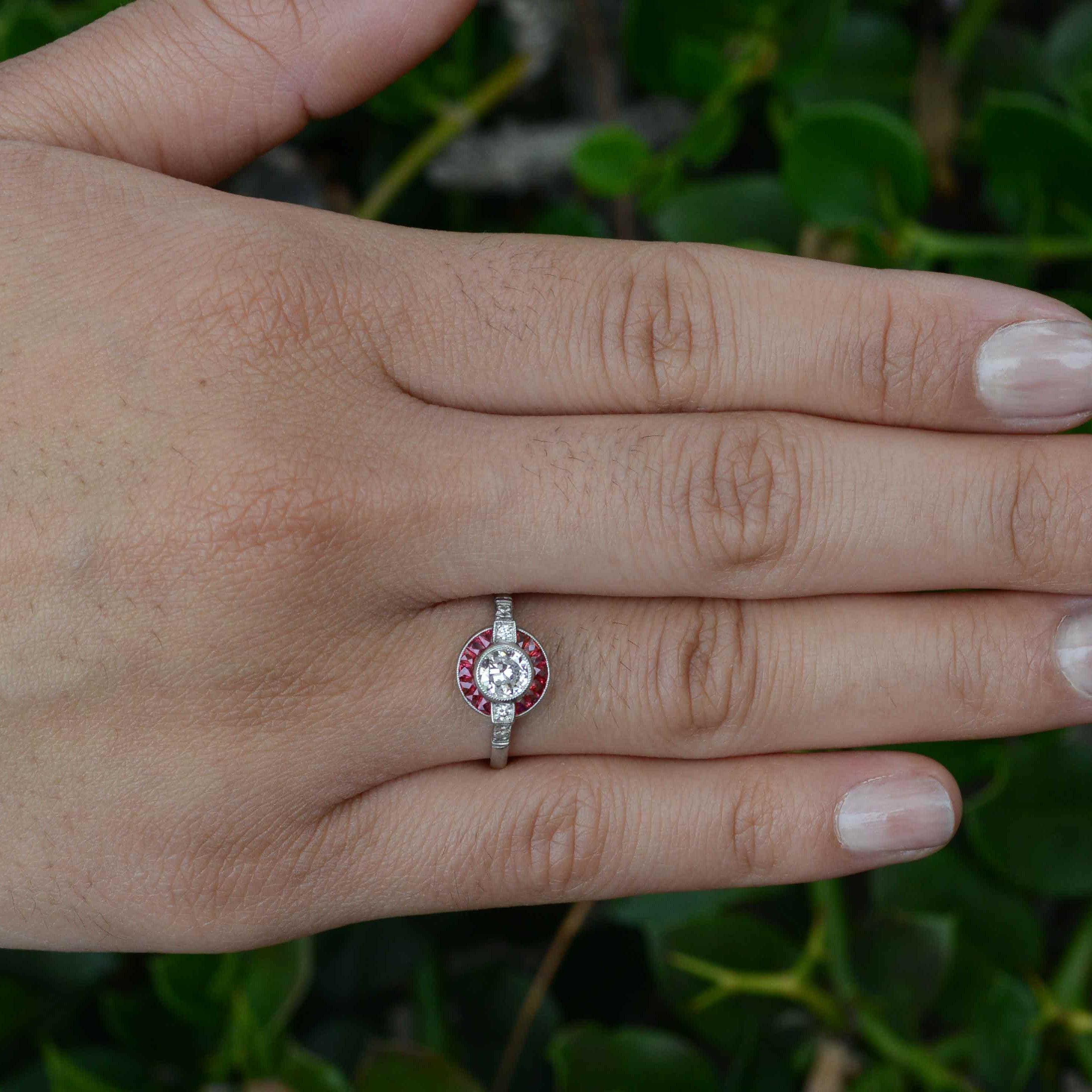 An old European brilliant diamond engagement ring surrounded by a circular halo of rubies.