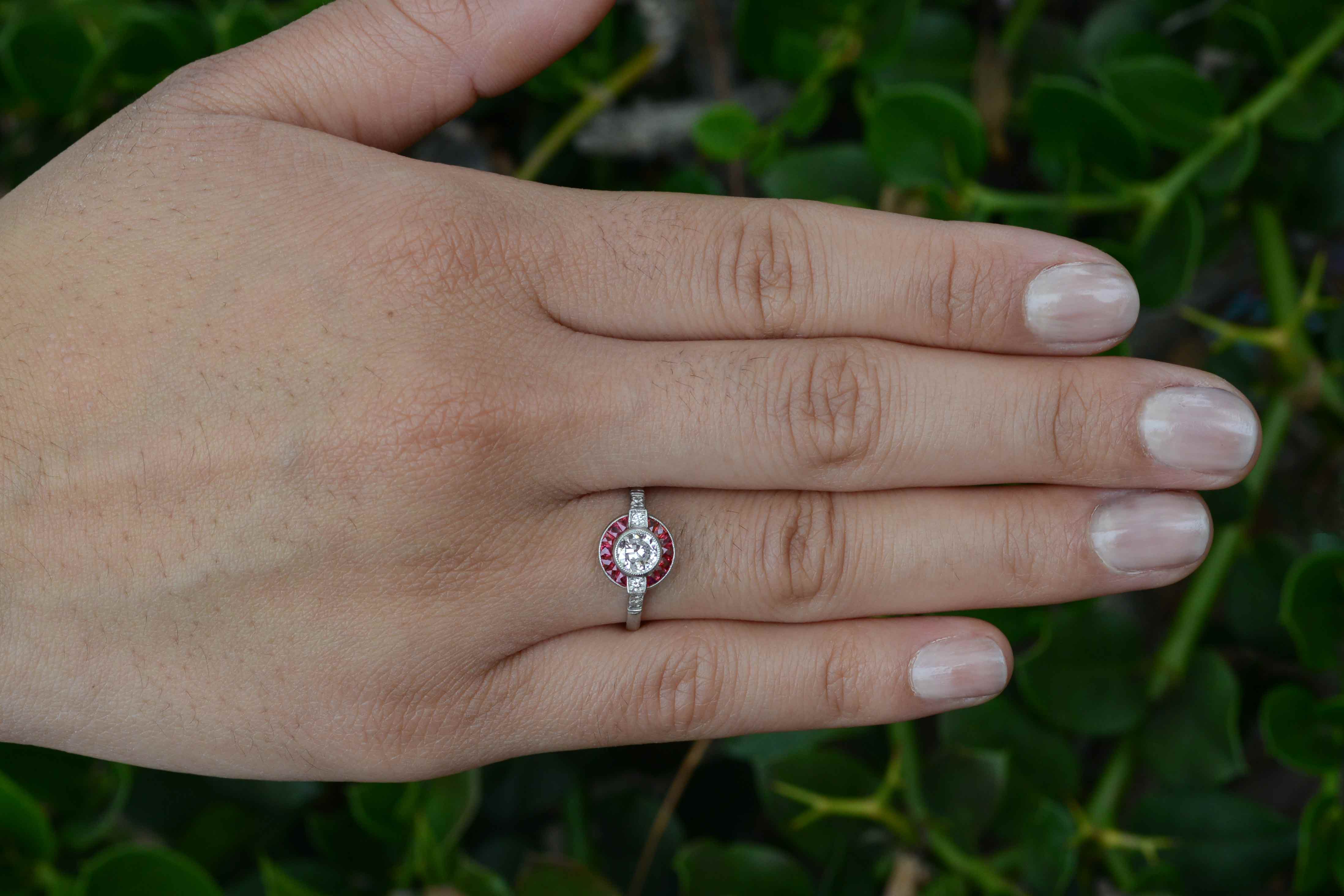 An old European brilliant diamond engagement ring surrounded by a circular halo of rubies.