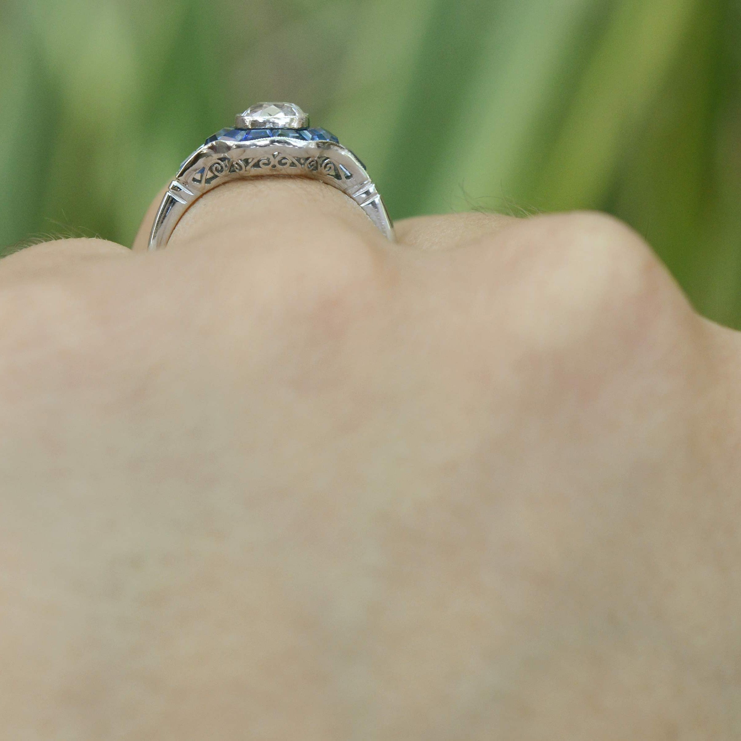 A filigree undergallery supports this single diamond and blue sapphires cluster ring.