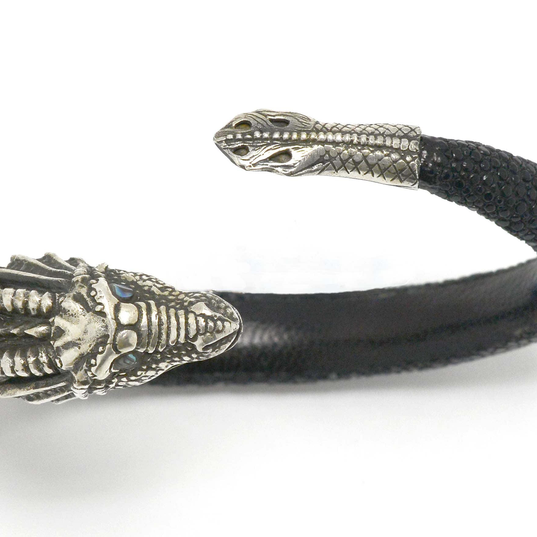 Silver arm cuff bangle and black leather wrap bracelet.