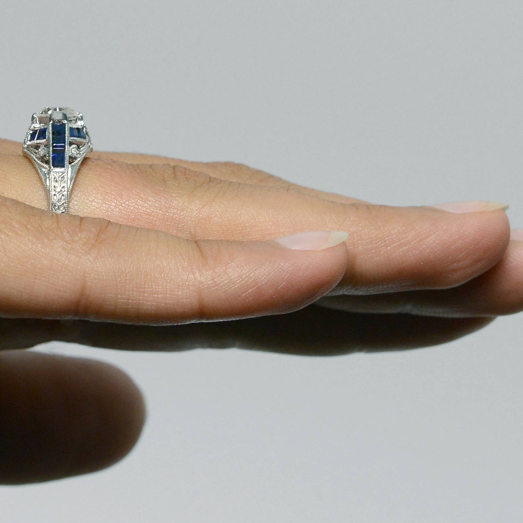 There is a blue sapphire cross pattern in this diamond Art Deco engagement ring.