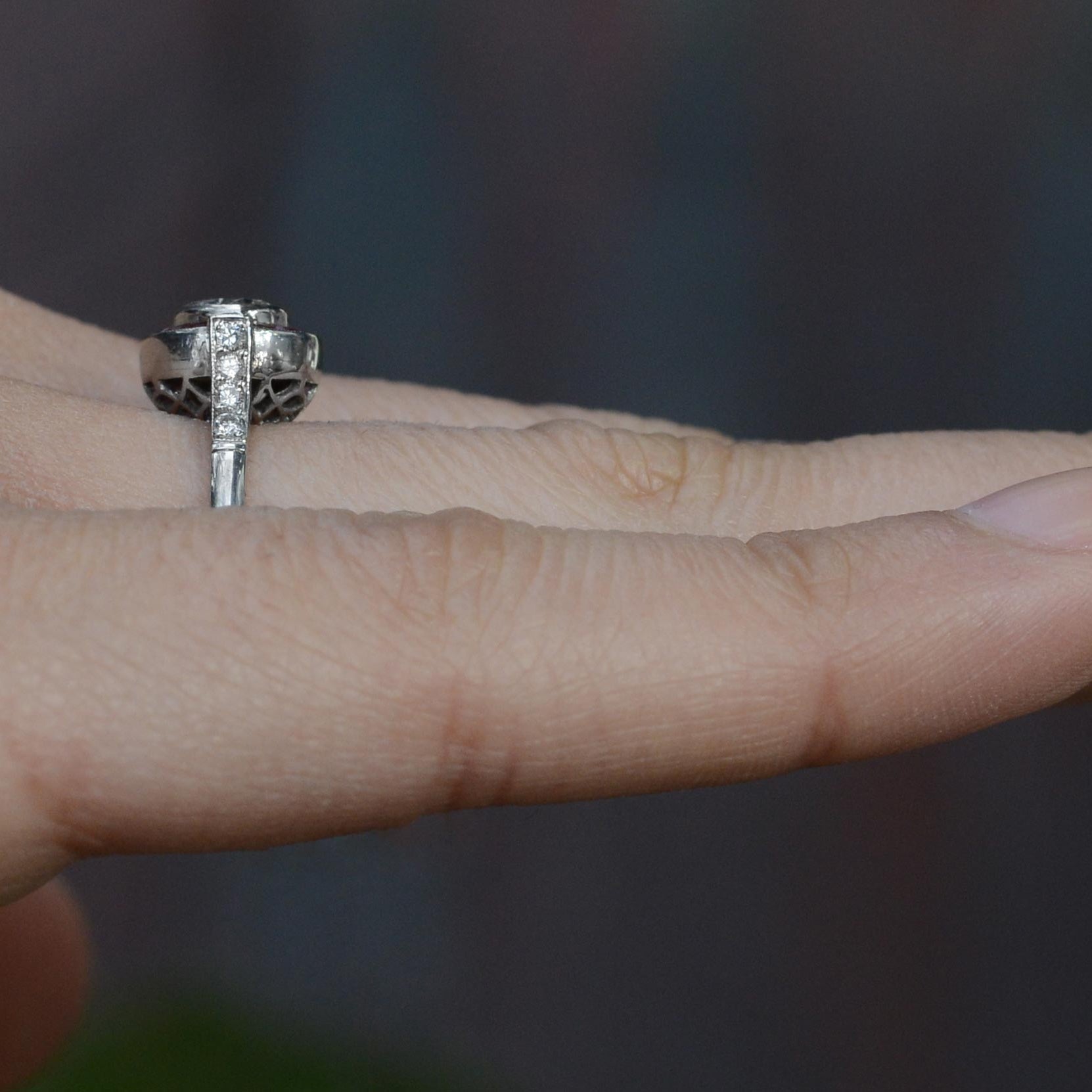 This ruby halo bridal ring has diamonds lined on the shoulder of the band.