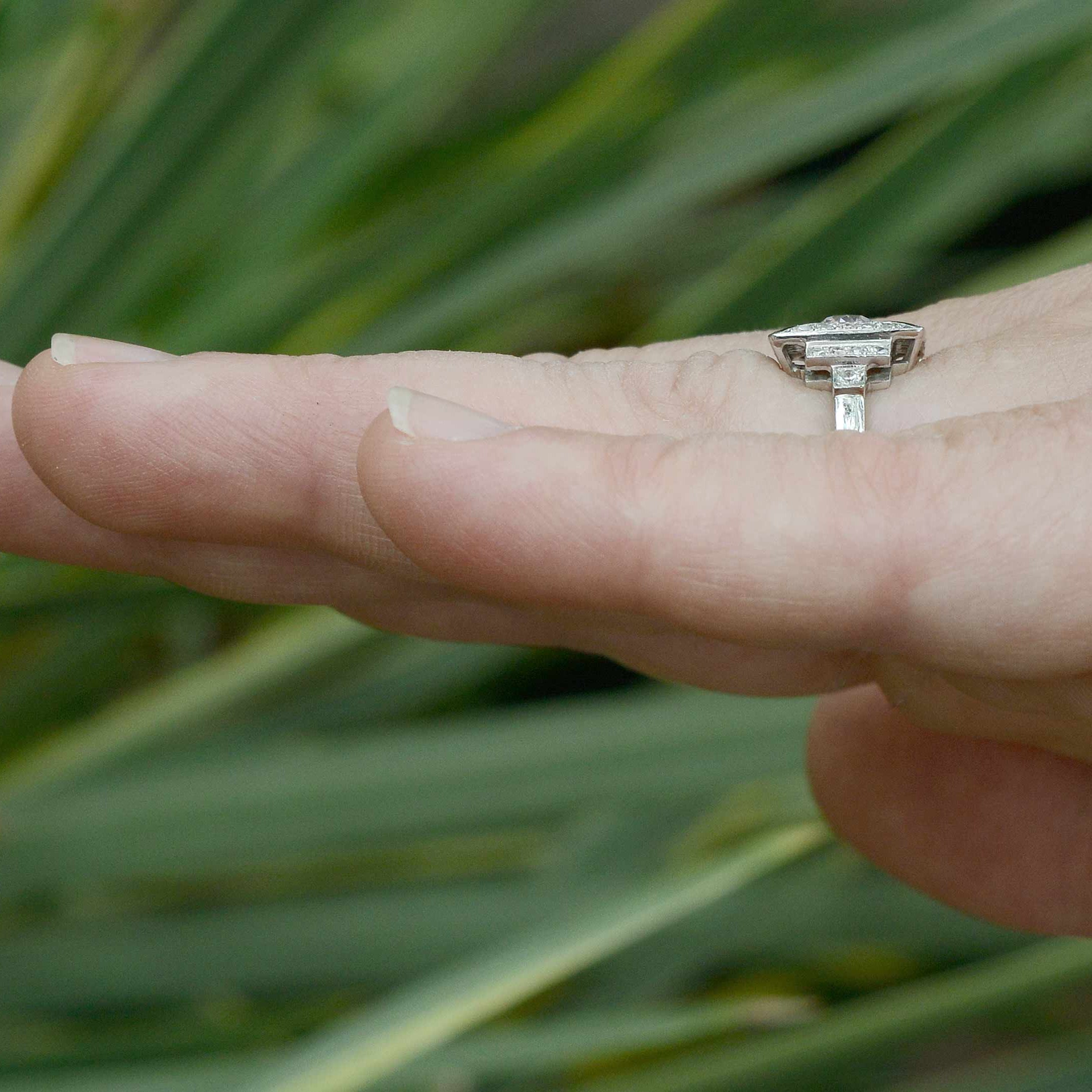 A tier design on the shoulders of this diamond engagement ring lined with black enamel.