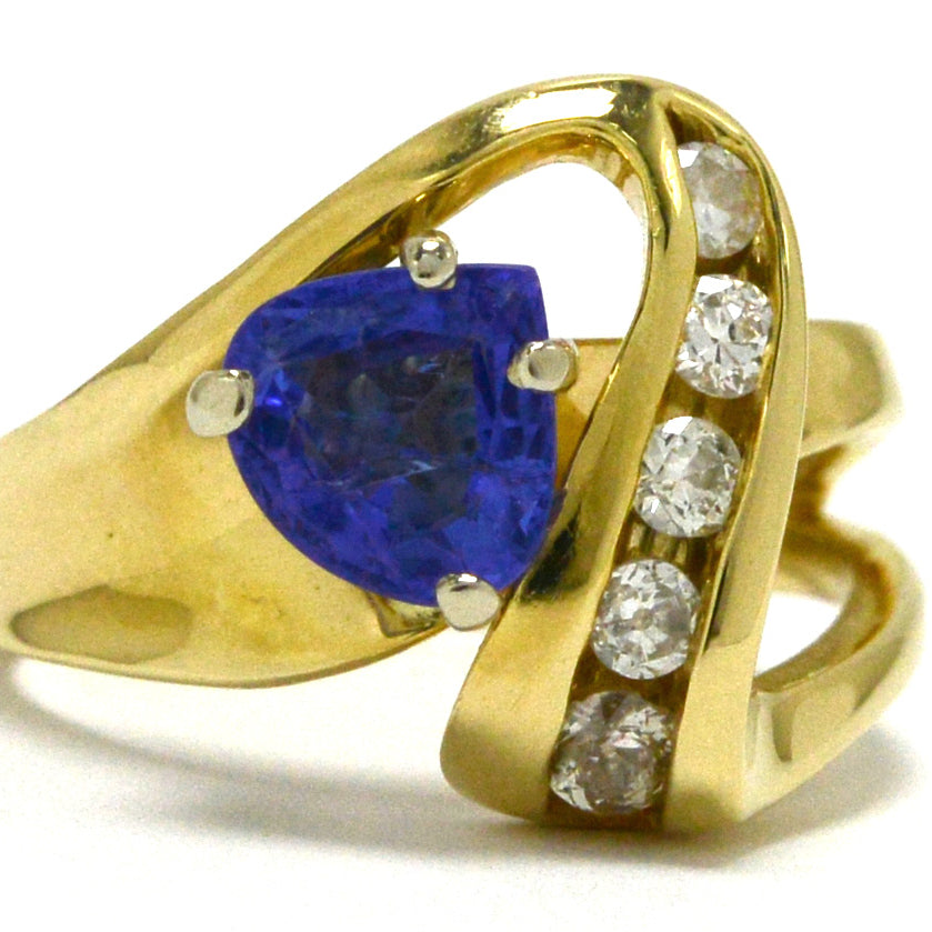 A modern trillion cut tanzanite 14k gold ring, with openwork set diamonds.