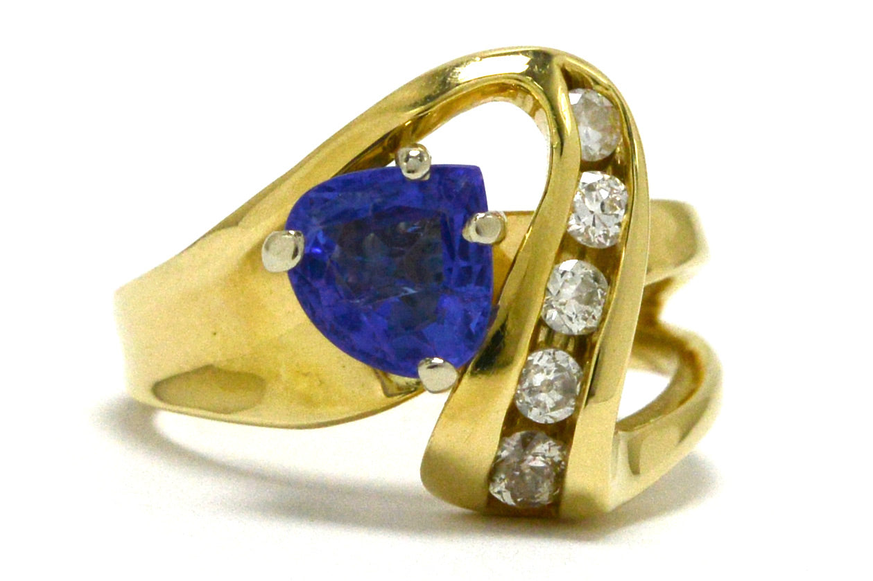 A modern trillion cut tanzanite 14k gold ring, with openwork set diamonds.