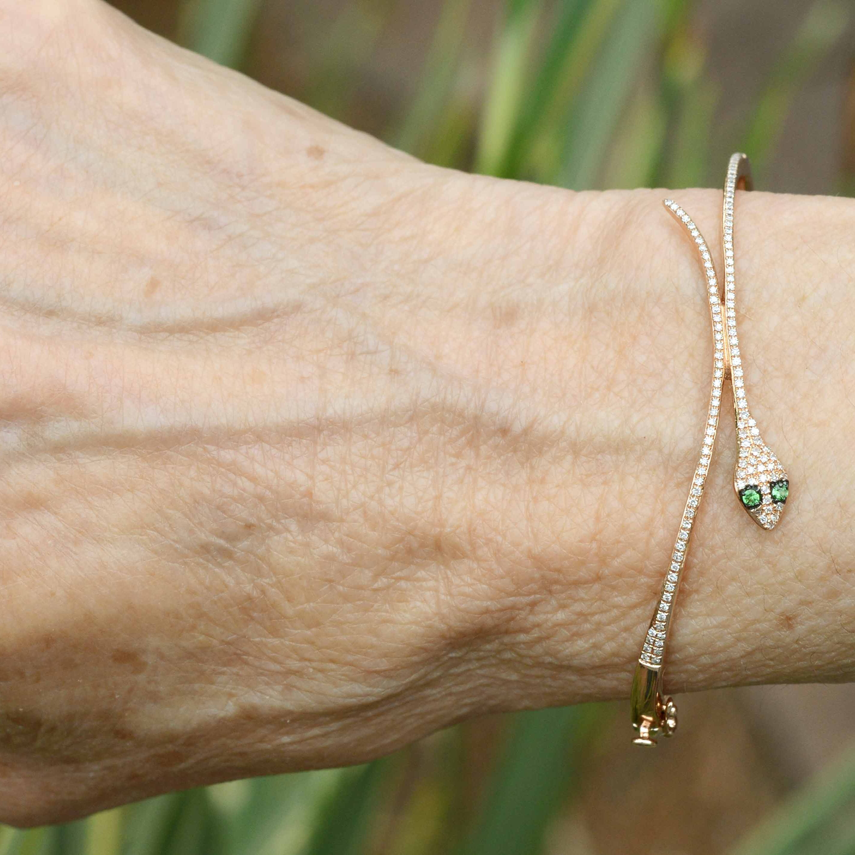 A thin round diamond rose gold snake bracelet with tsavorite eyes.