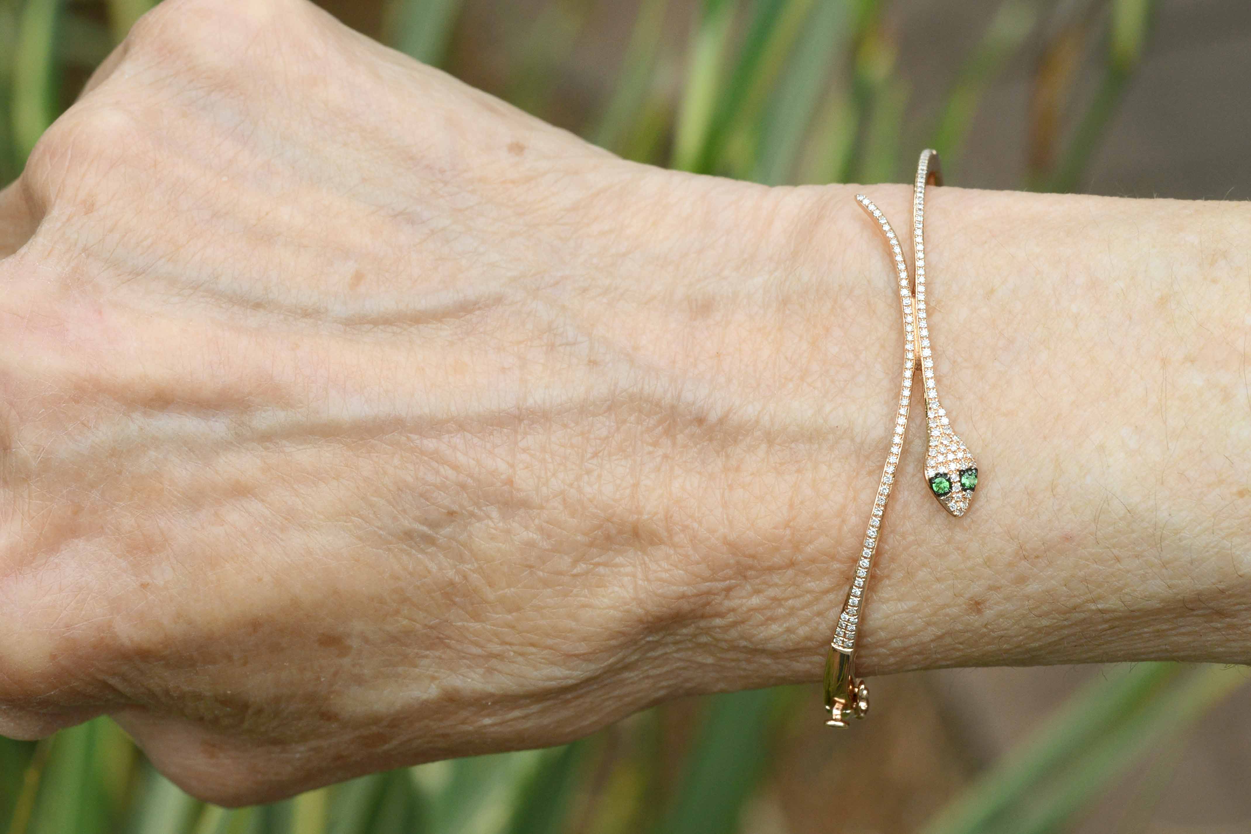 A thin round diamond rose gold snake bracelet with tsavorite eyes.