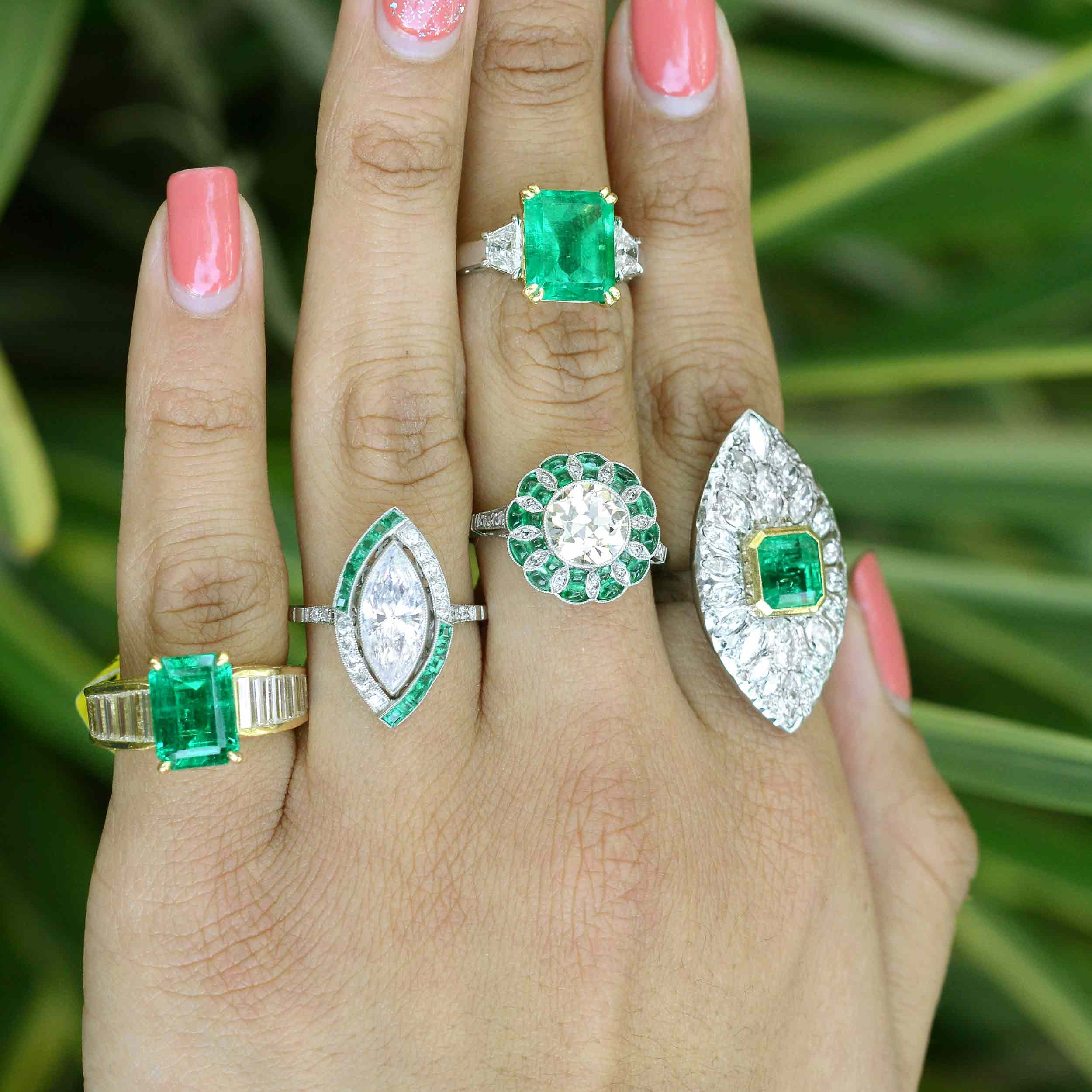 A set of engagement rings with large diamond and emerald center gemstones.