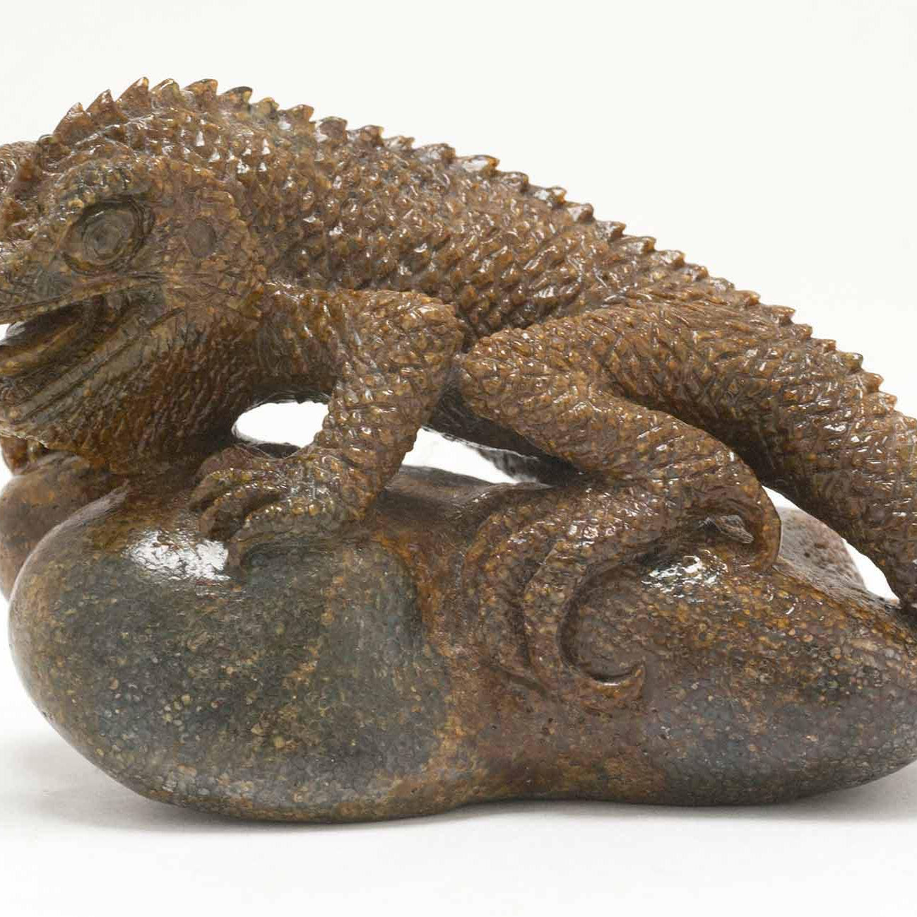 A perched lizard figure, carved out of fossilized whale bone by Ronald Stevens.