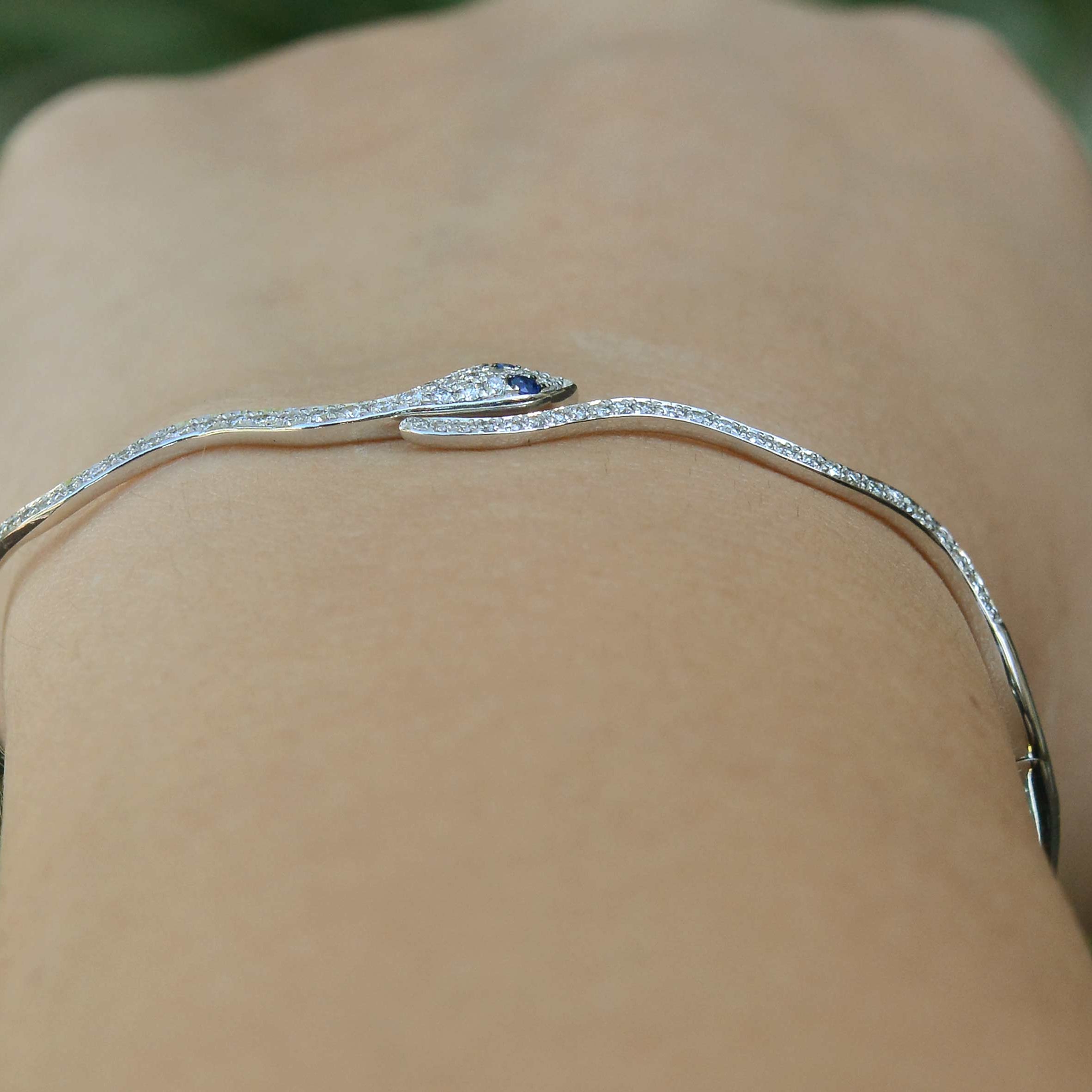 A thin, white gold hinged bangle bracelet.