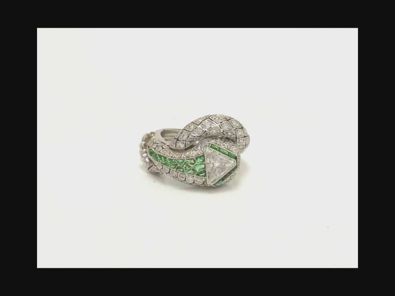 An emerald snake ring with unique triangular diamond filigree scales along its body. 