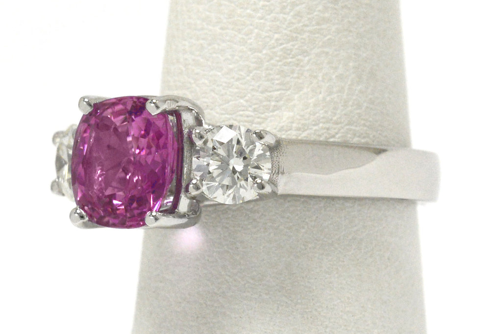 The antique cushion pink sapphire is accented by 2 white diamonds.