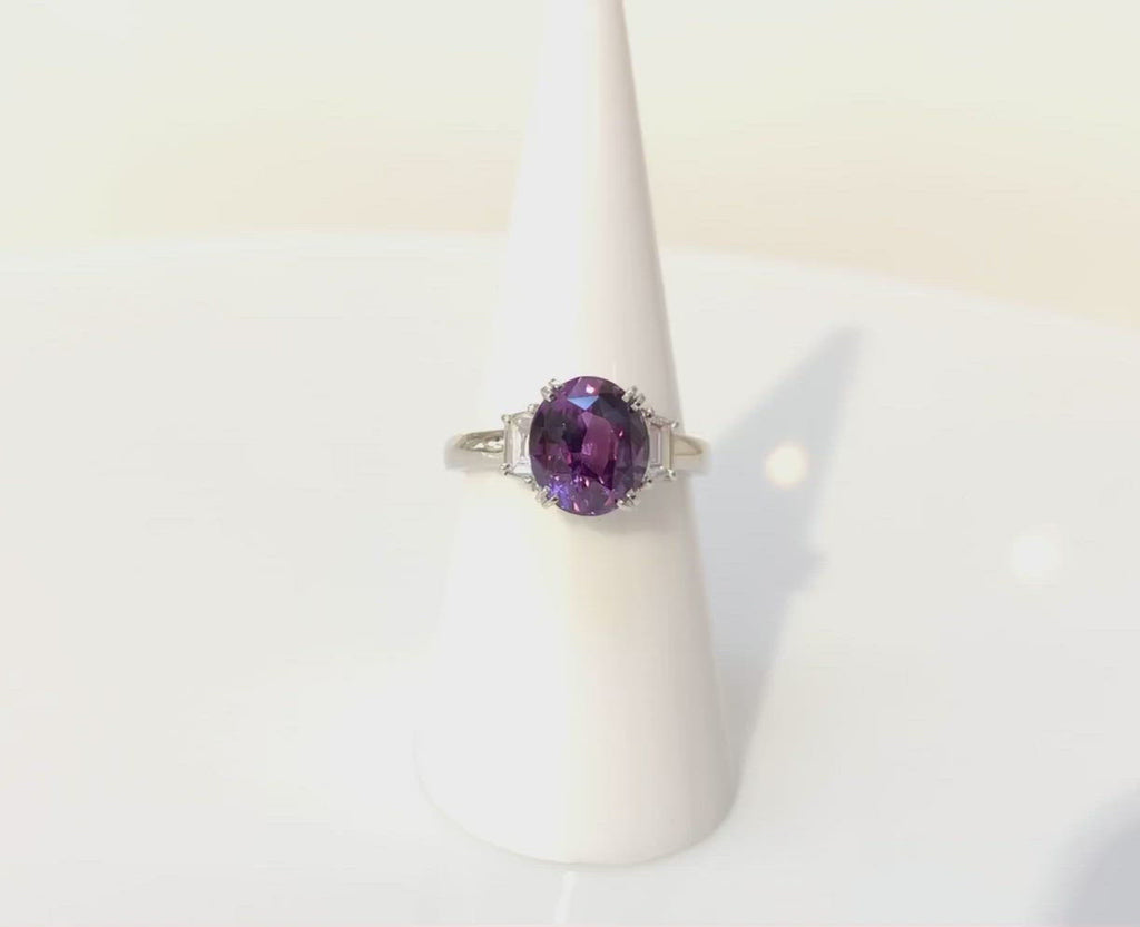 A medium pinkish lavender purple 3 carat sapphire trinity engagement ring with diamonds.