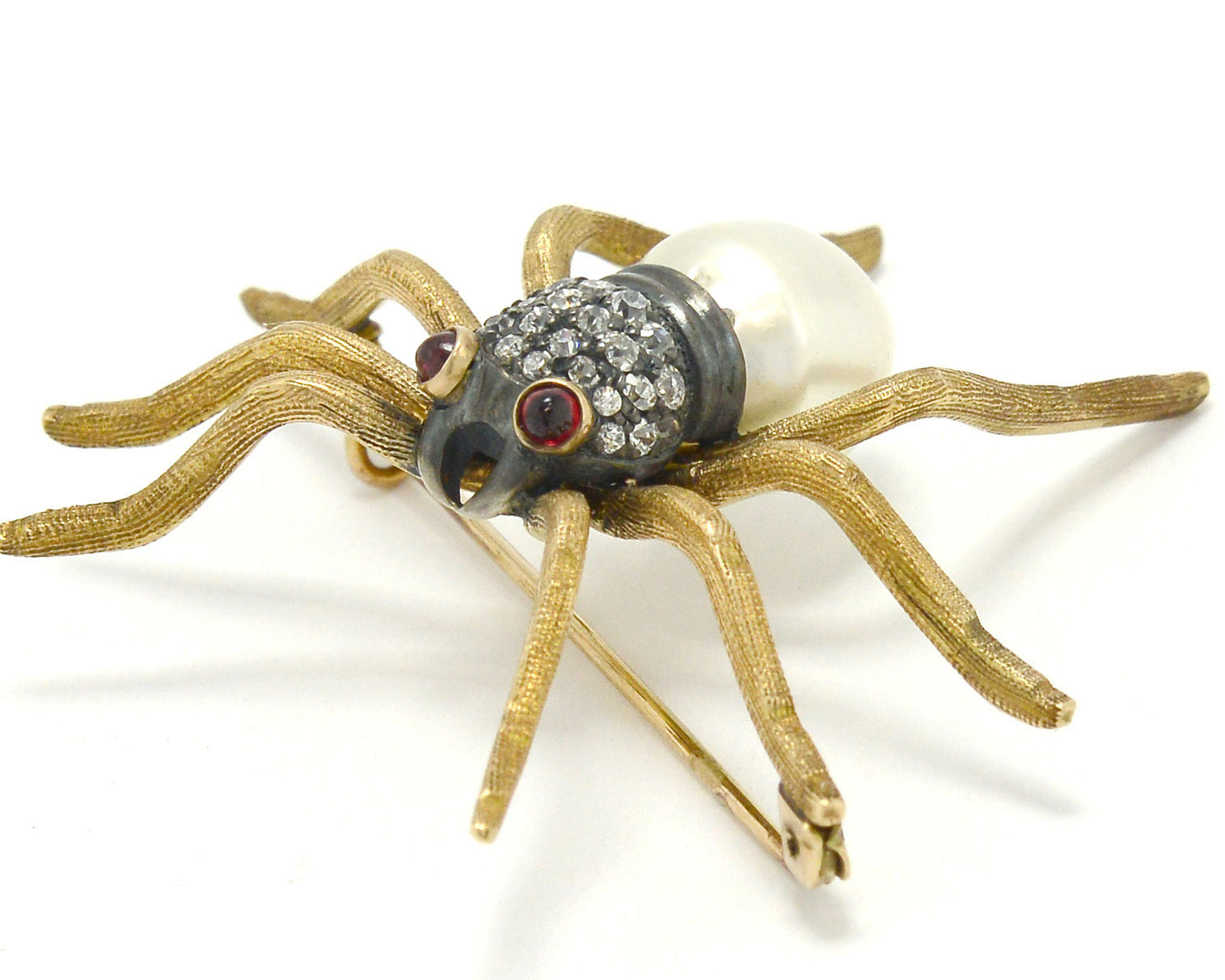 An antique Victorian spider pin made of gold, rubies, diamonds and pearl.